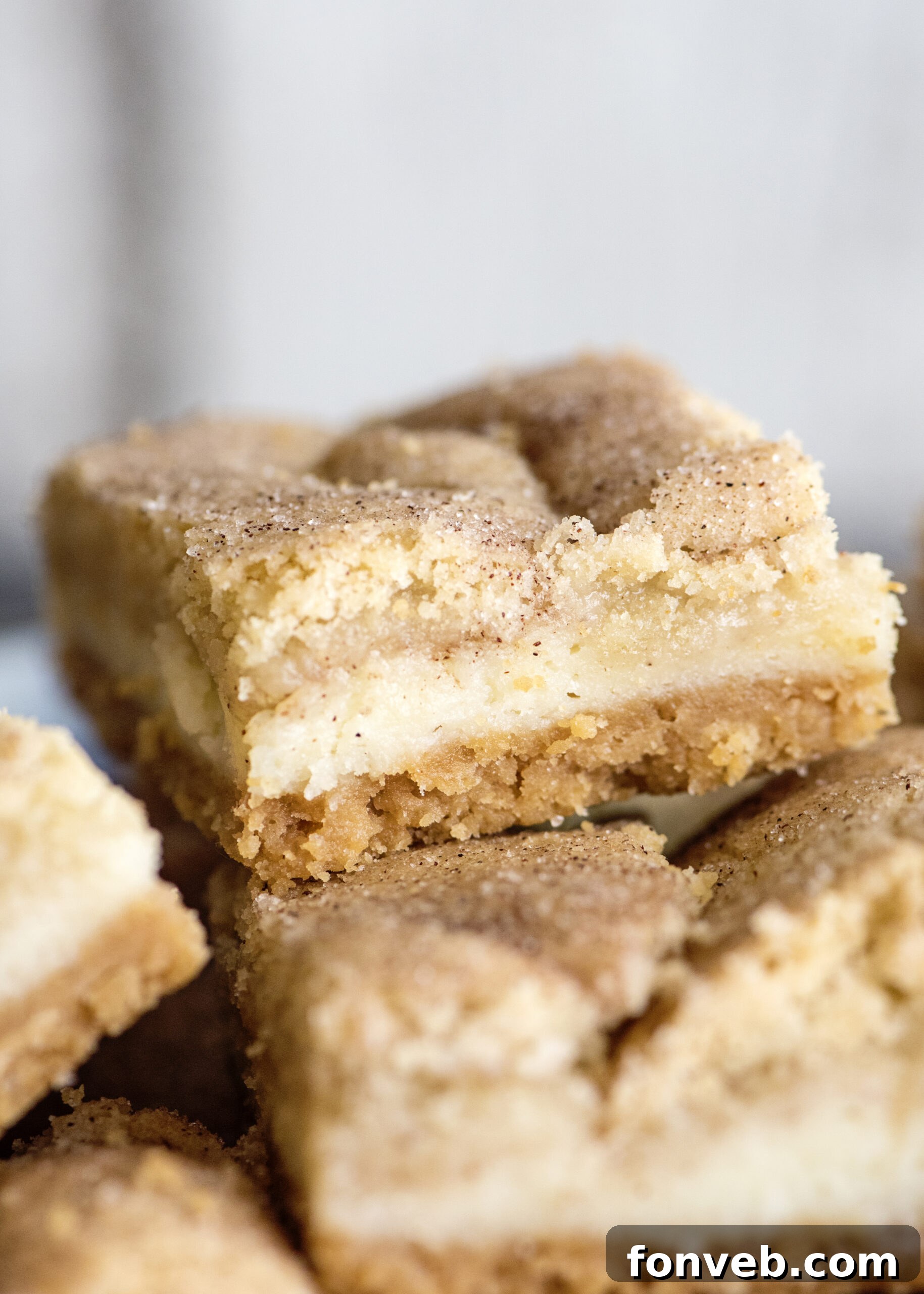 Several Snickerdoodle Cheesecake Bars neatly cut and arranged on a parchment-lined tray