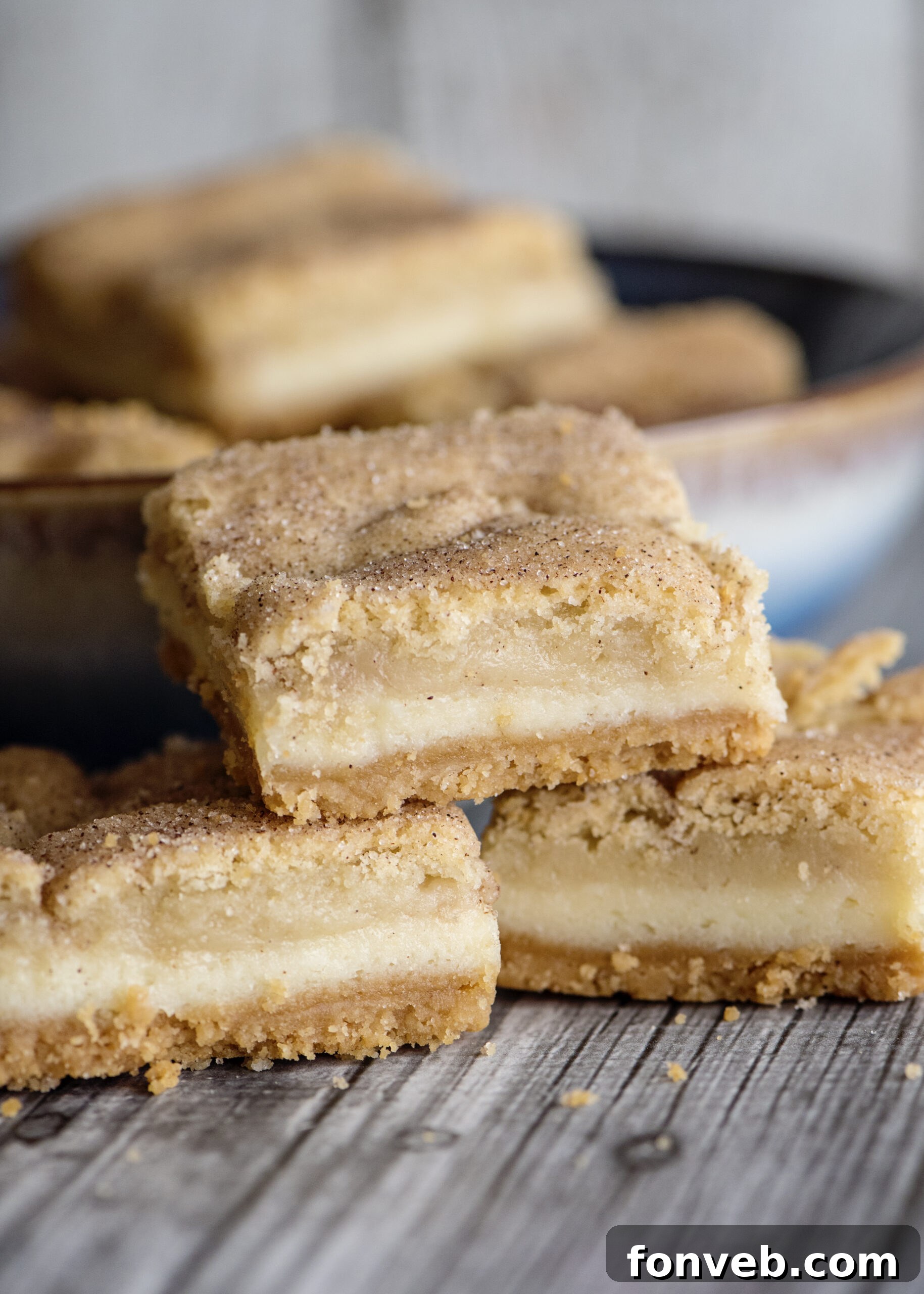 Snickerdoodle Cheesecake Bars with a bite taken out, showing the layers