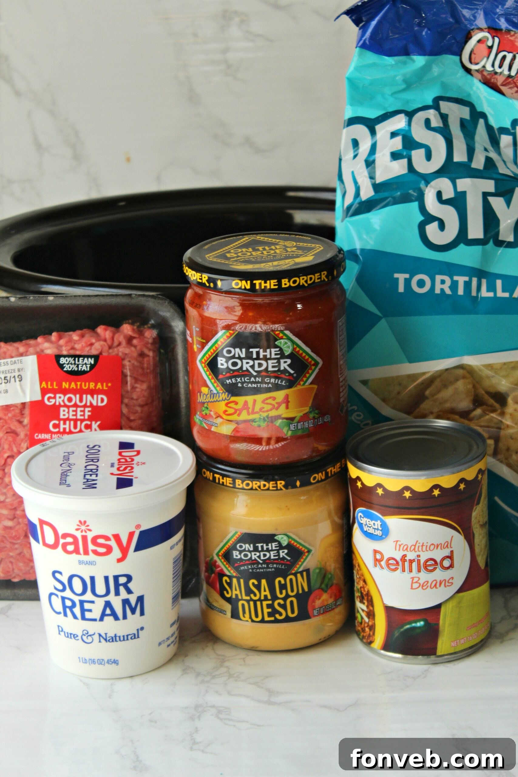 Warm and cheesy slow cooker taco dip served in a crock pot with tortilla chips
