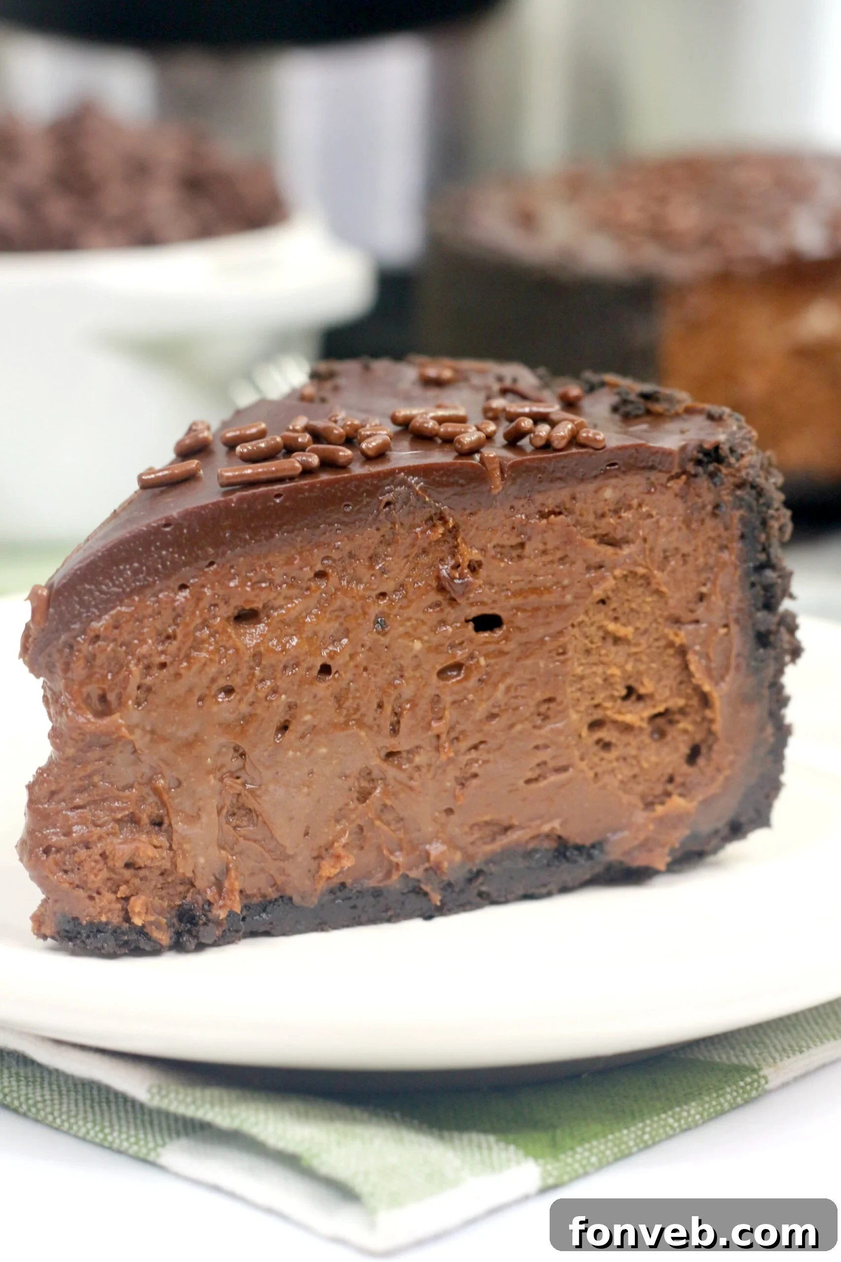 A stunning slice of Instant Pot Death by Chocolate Cheesecake with ganache and sprinkles