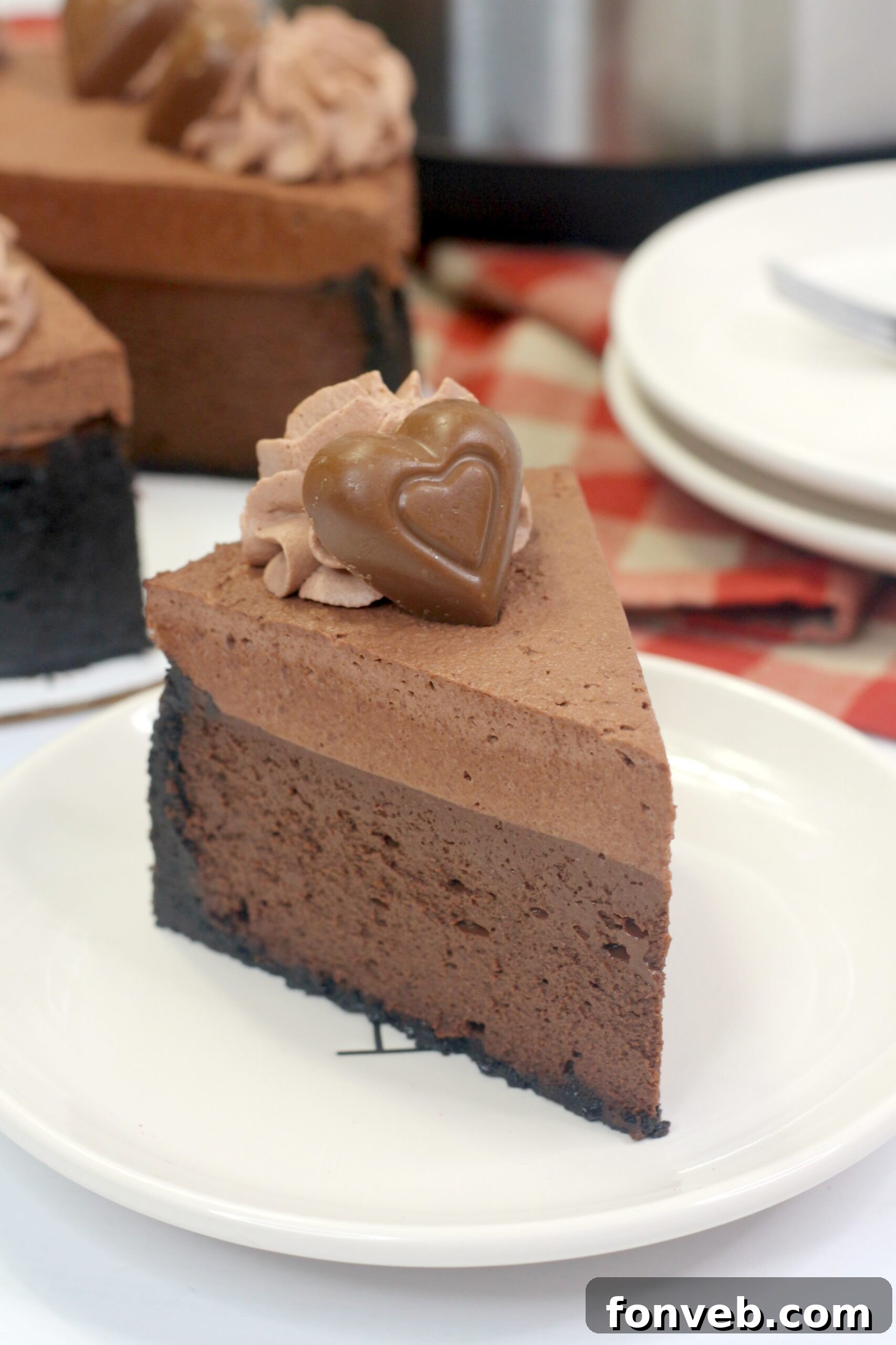 Side view of the Triple Chocolate Layered Godiva Cheesecake, highlighting the height and distinct layers of crust, cheesecake, and toppings.