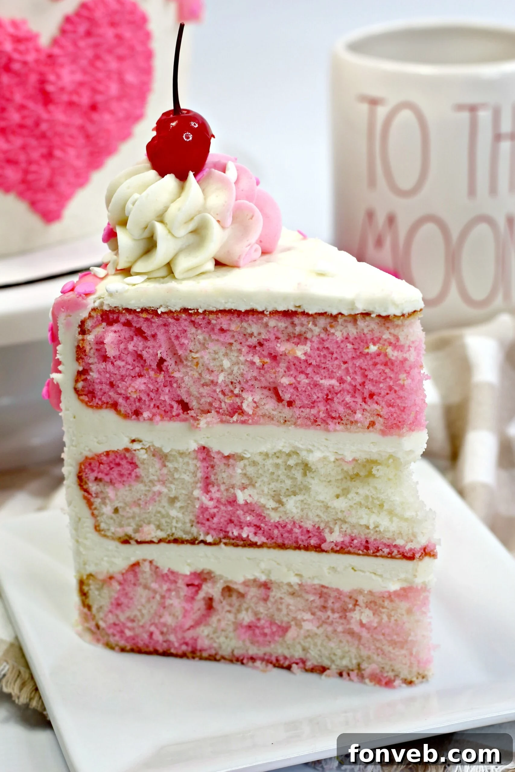 Close-up of a slice of Valentine’s Day Love Cake revealing its moist, multi-layered pink and white interior.