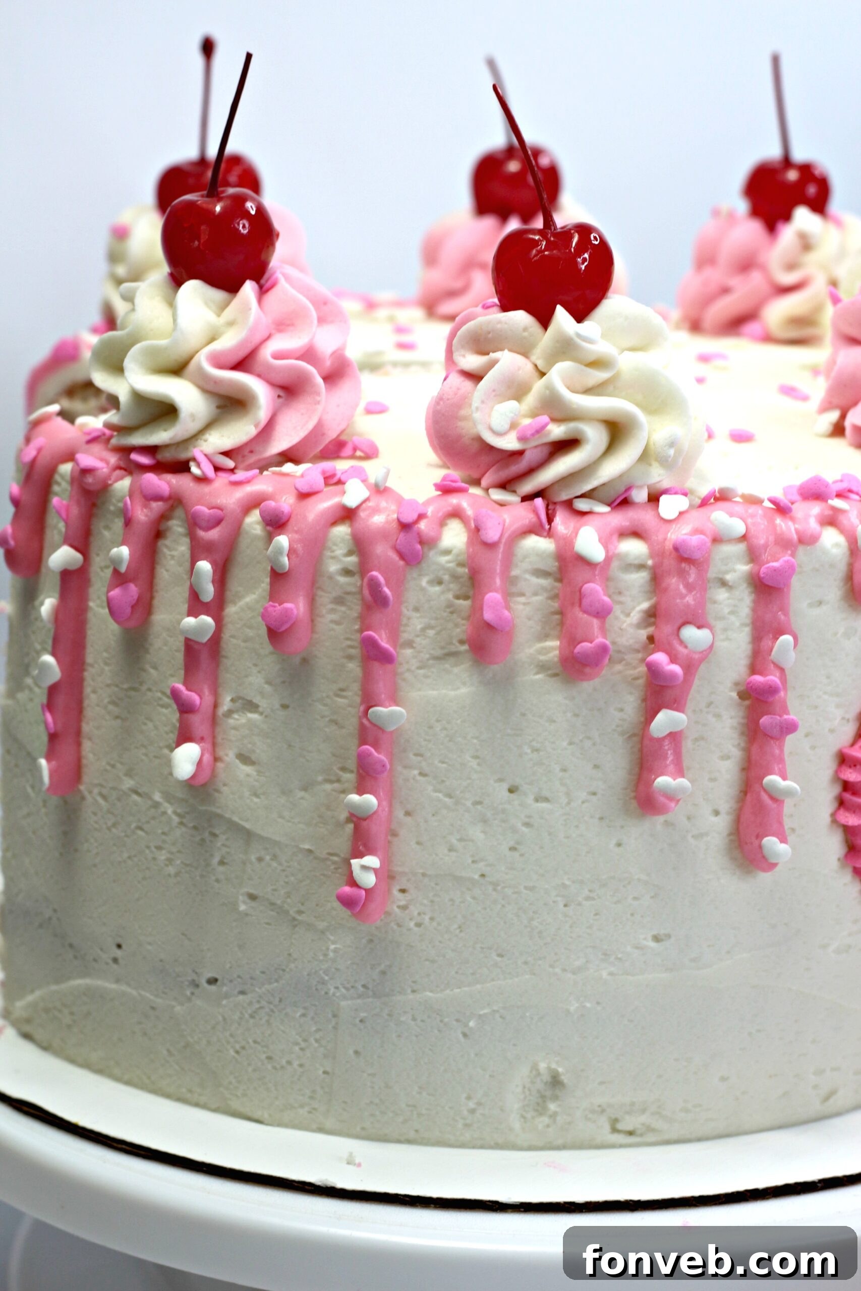The full Valentine’s Day Love Cake decorated with various pink frosting dollops and heart sprinkles.