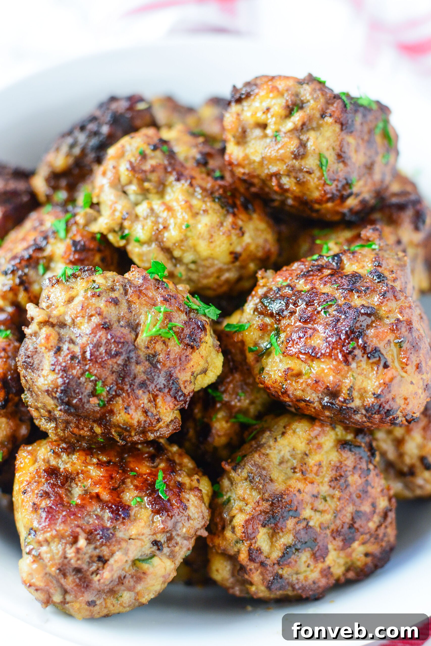 Plate of spaghetti and baked Italian meatballs, garnished with fresh basil.