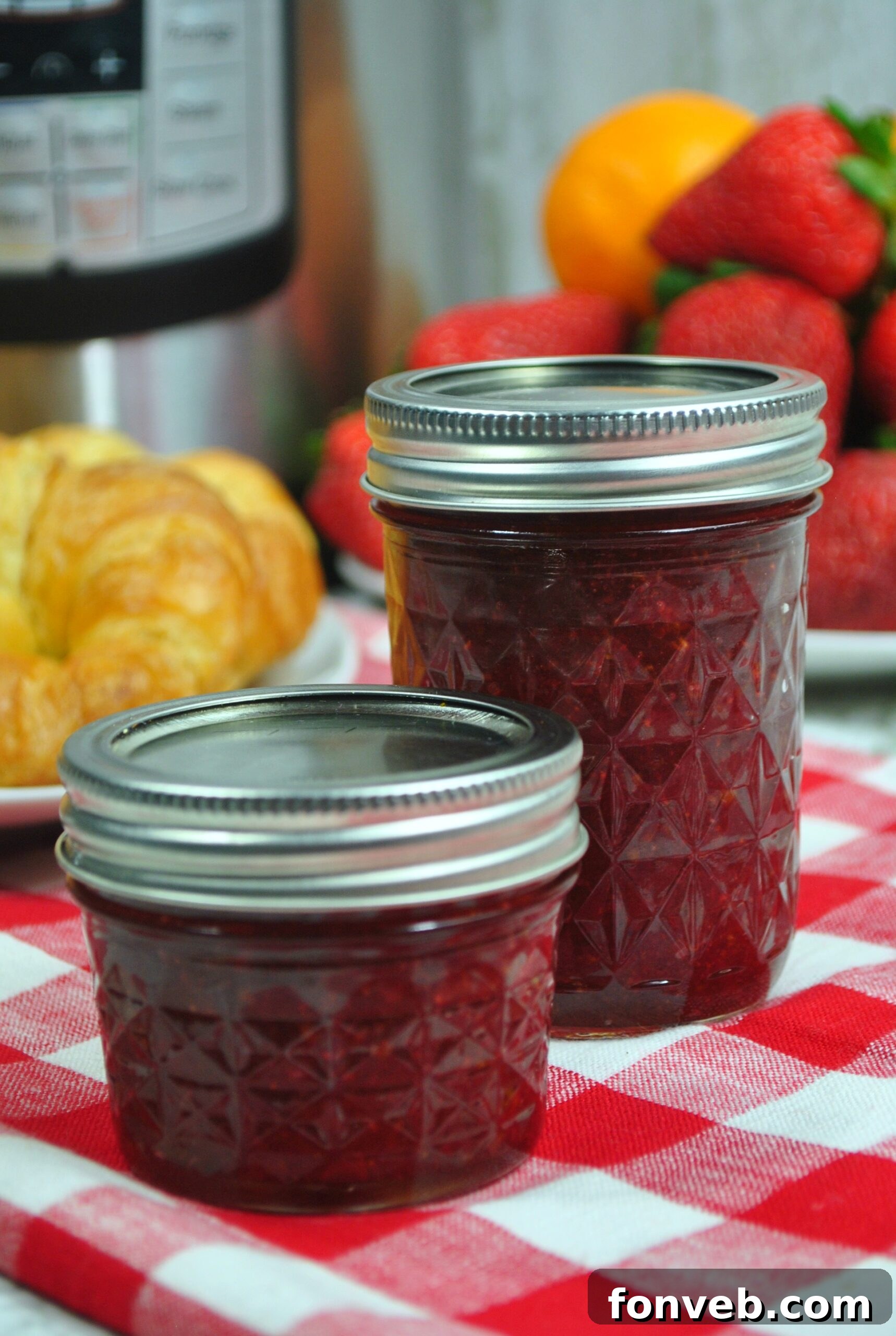 Jar of strawberry jam next to fresh strawberries