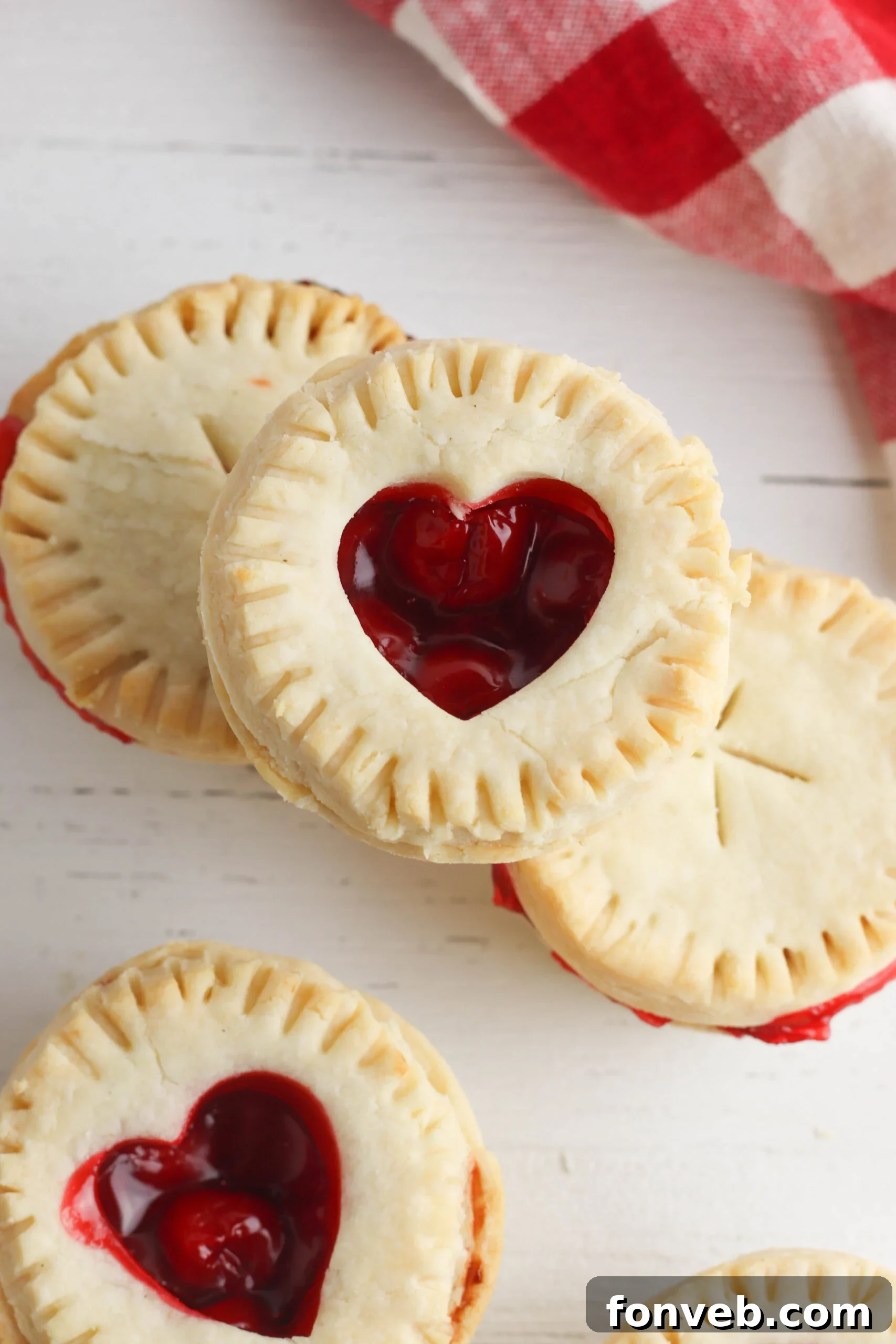 Close-up of a rustic, golden-brown mini cherry pie, showcasing its flaky crust and vibrant filling.