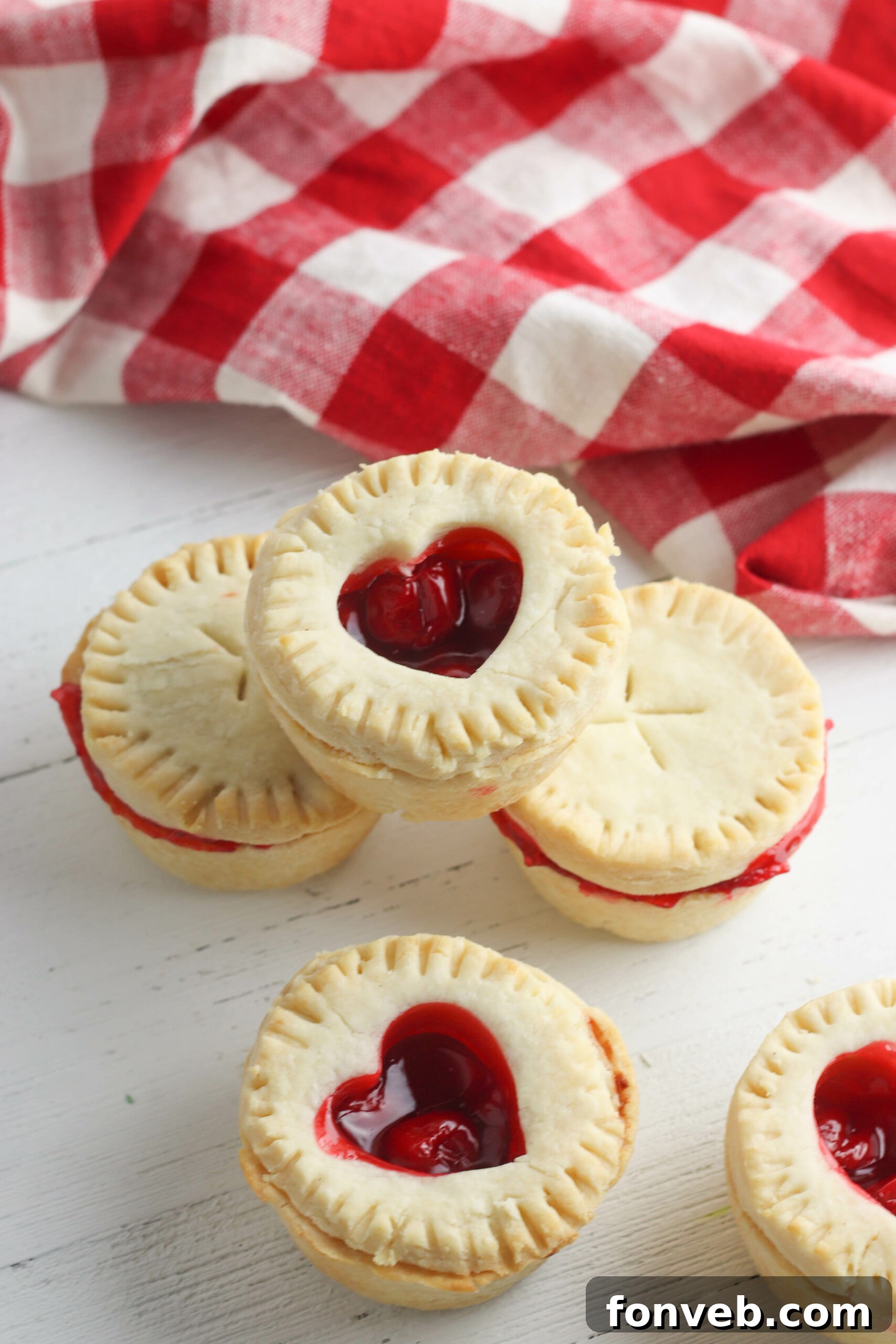 Several mini cherry pies arranged neatly on a wooden surface, ready to be served or enjoyed.