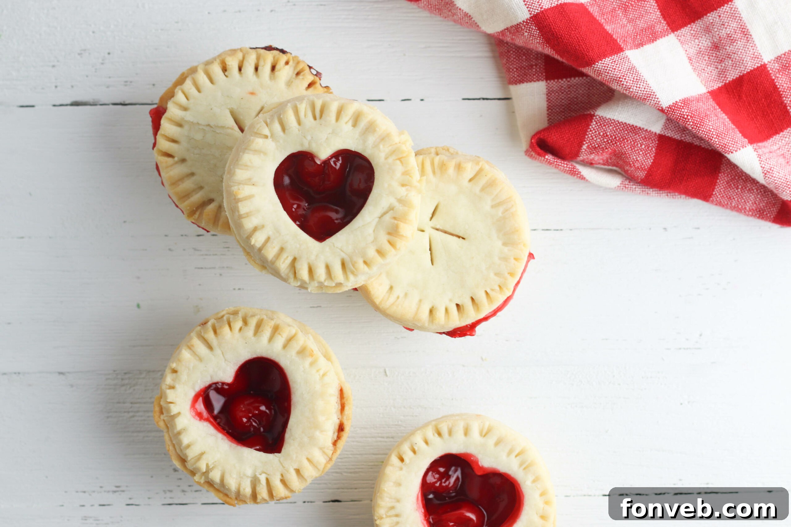 A close-up shot of a baked mini cherry pie with a golden-brown, decorative crust.