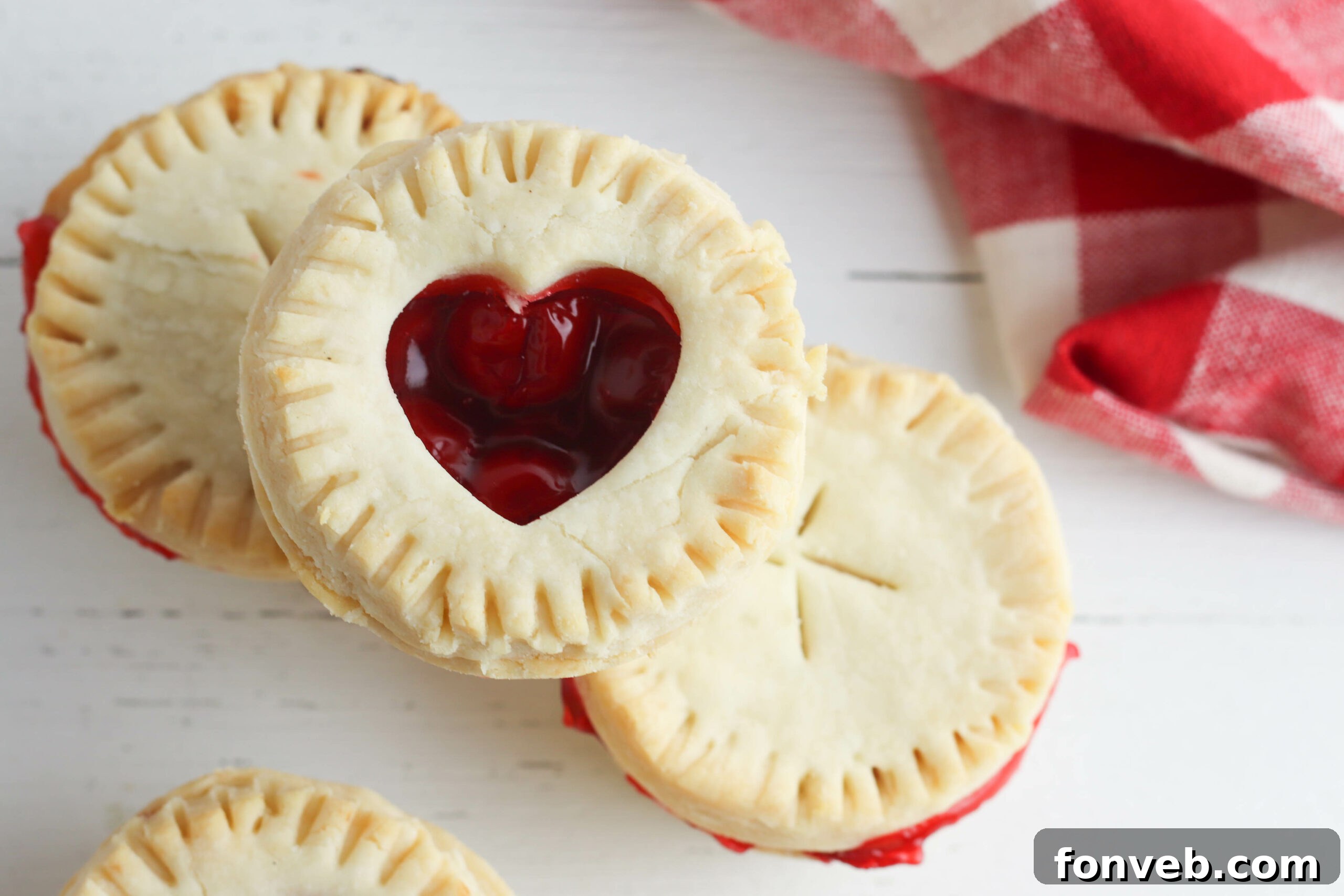 An array of mini cherry pies, some with fruit visible, on a serving platter, highlighting their perfect size.