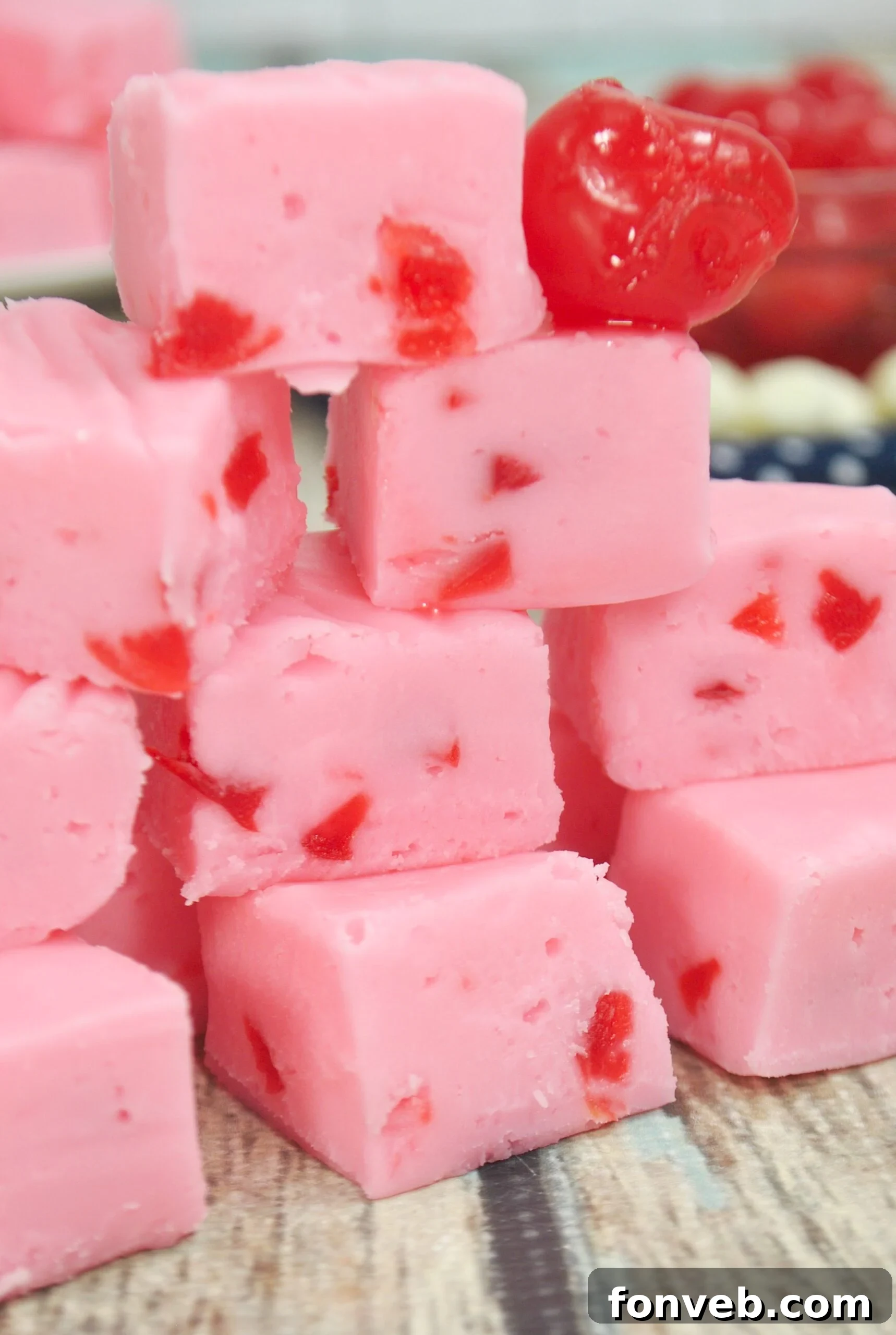 Close-up of freshly made cherry fudge squares, showing the creamy pink texture and visible maraschino cherry pieces.