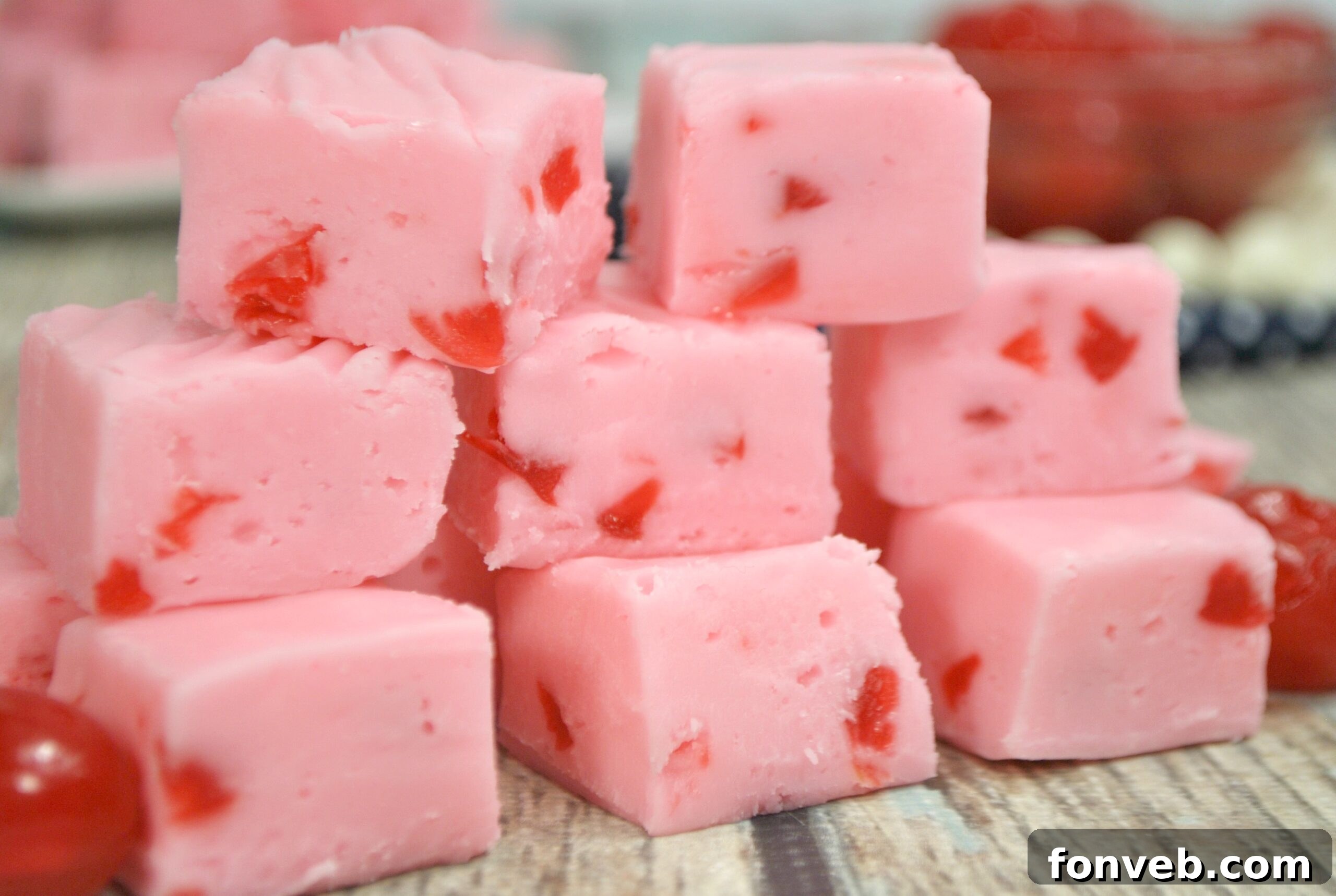 Overhead shot of cherry fudge being cut into squares in a parchment-lined pan, showing the soft, smooth interior.