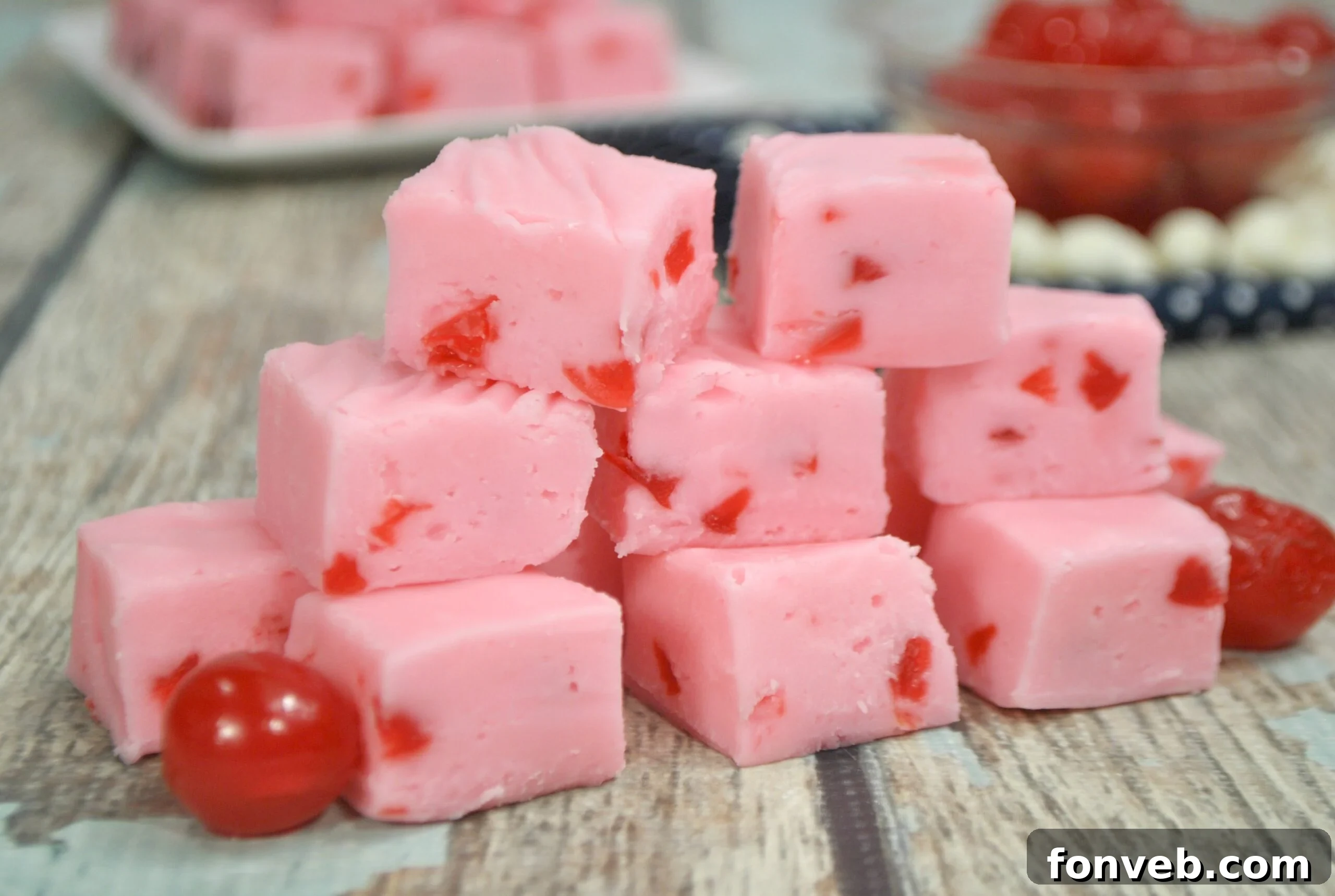 Various pieces of cherry fudge arranged artfully on a white surface, showcasing their perfect square shapes.