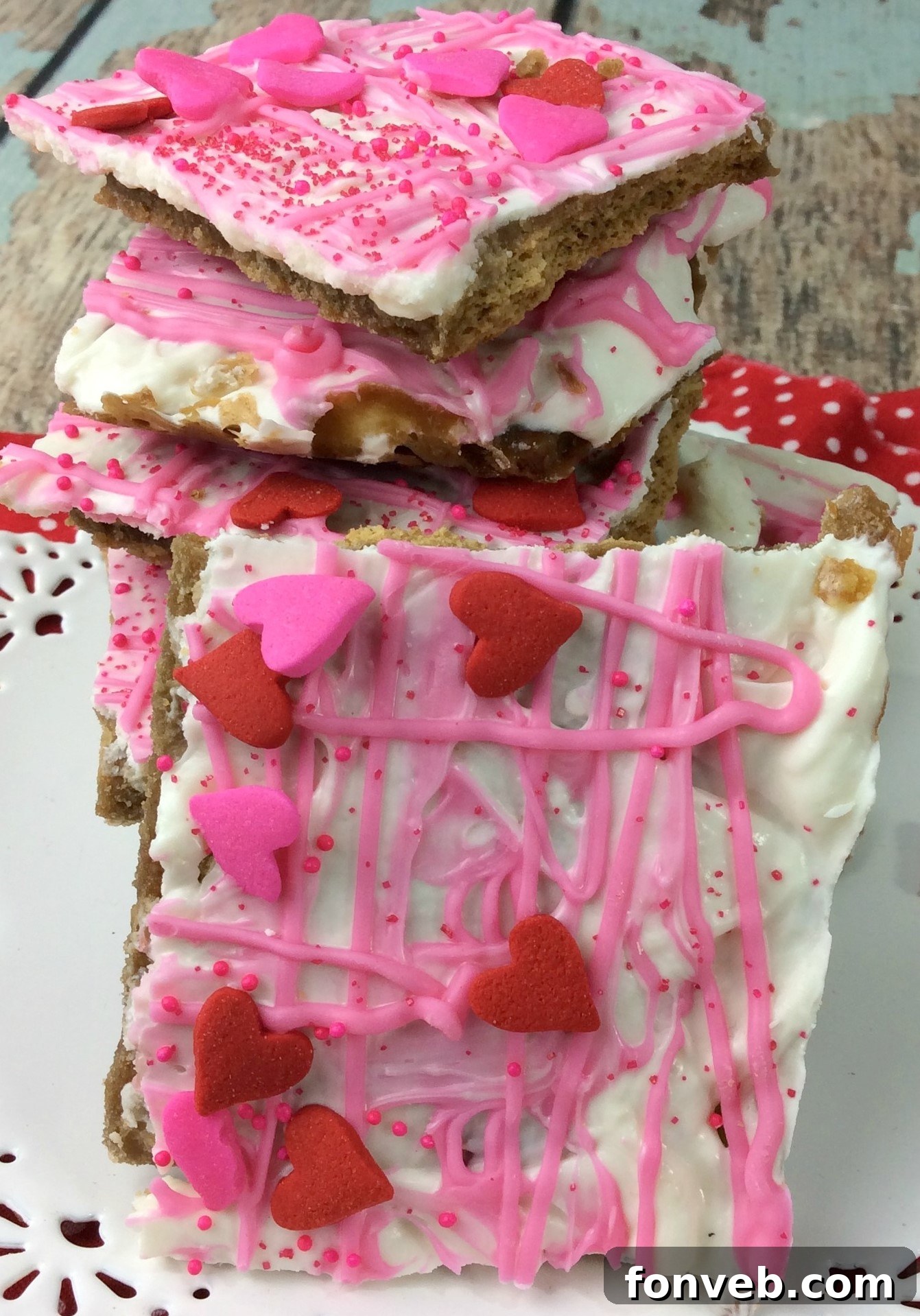 Valentine's Day Crack on a pink platter, featuring a colorful assortment of white chocolate bark with pink and red sprinkles and heart candies.