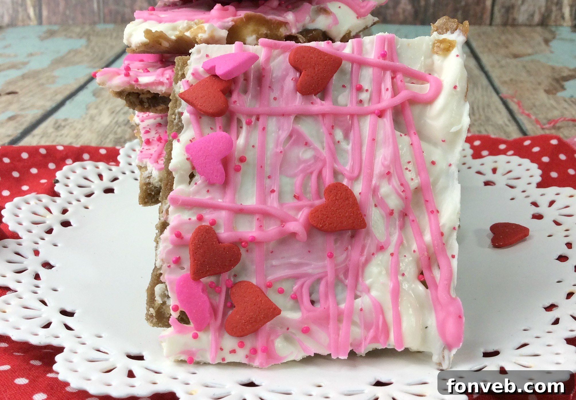Close-up of Valentine's Day Crack showing layers of white and pink chocolate, adorned with a variety of festive heart and spherical sprinkles.
