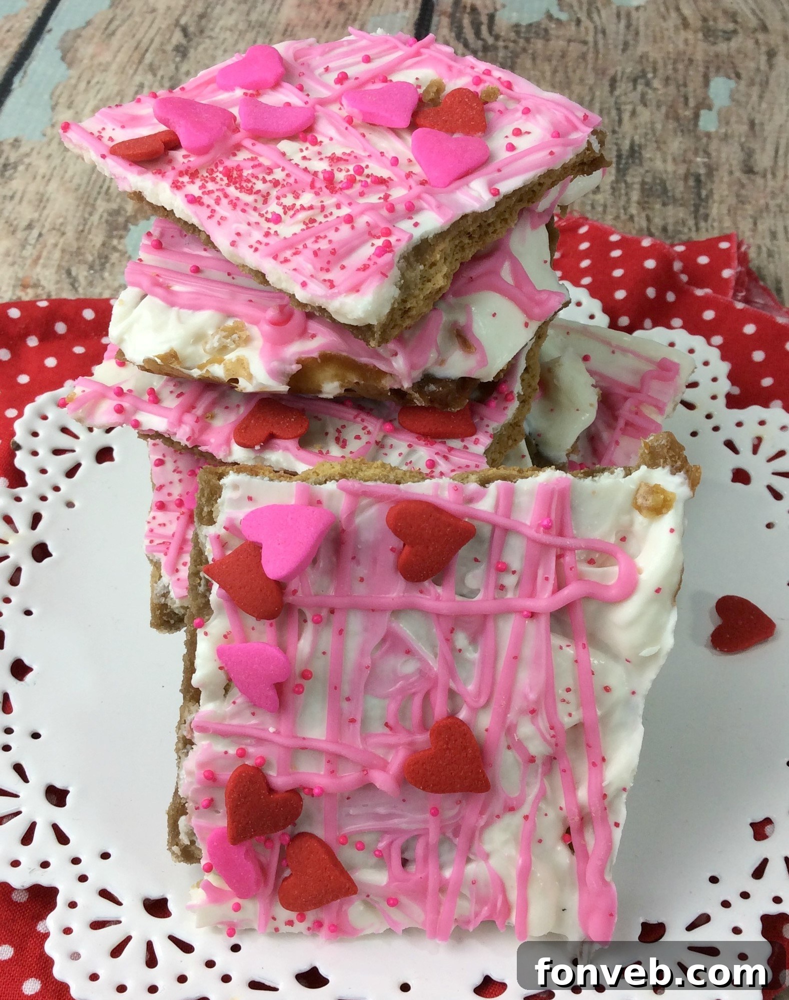 A batch of freshly made Valentine's Day Crack, set on a baking sheet, ready to be broken into pieces. The vibrant pink and white chocolates are generously topped with sprinkles.