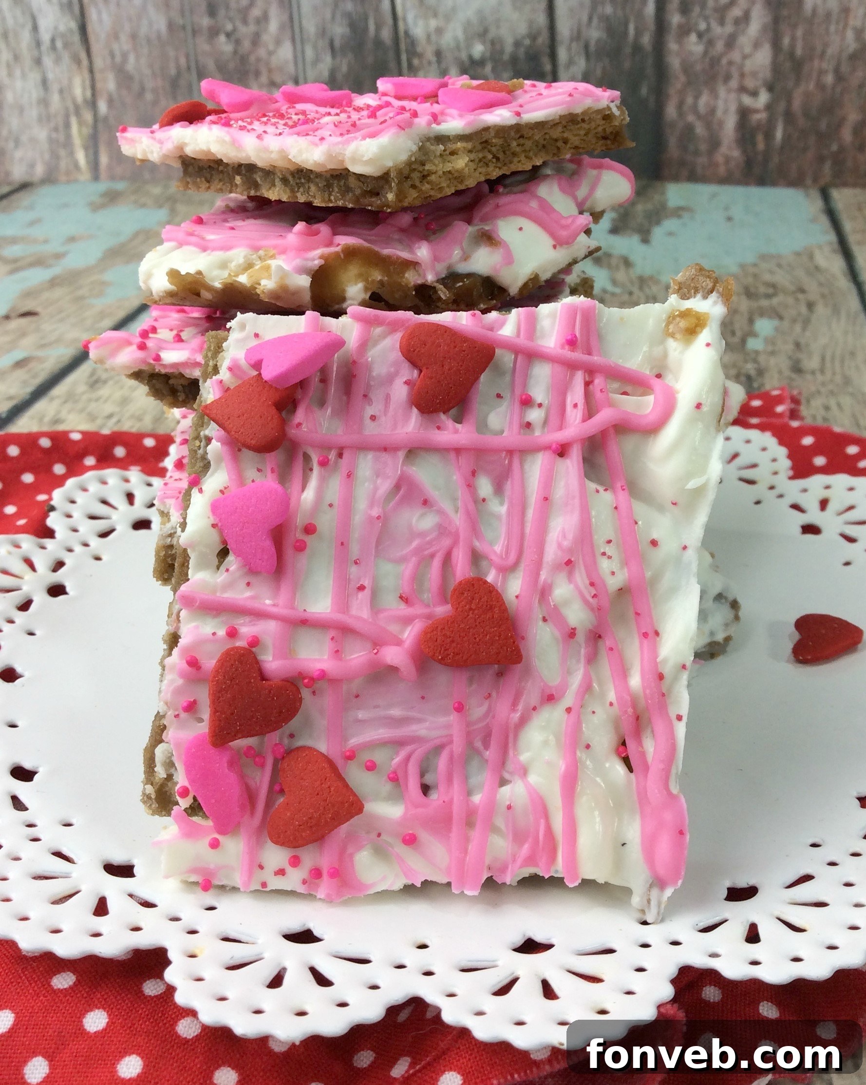 Hand holding a piece of Valentine's Day Crack, showcasing its thickness and the generous sprinkle topping.