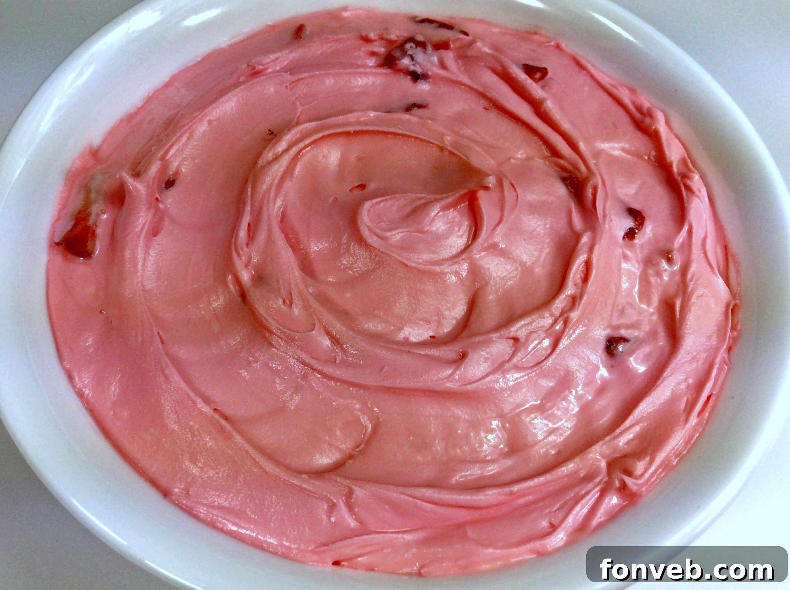 A bowl of creamy, pink strawberry buttercream frosting ready to be used.