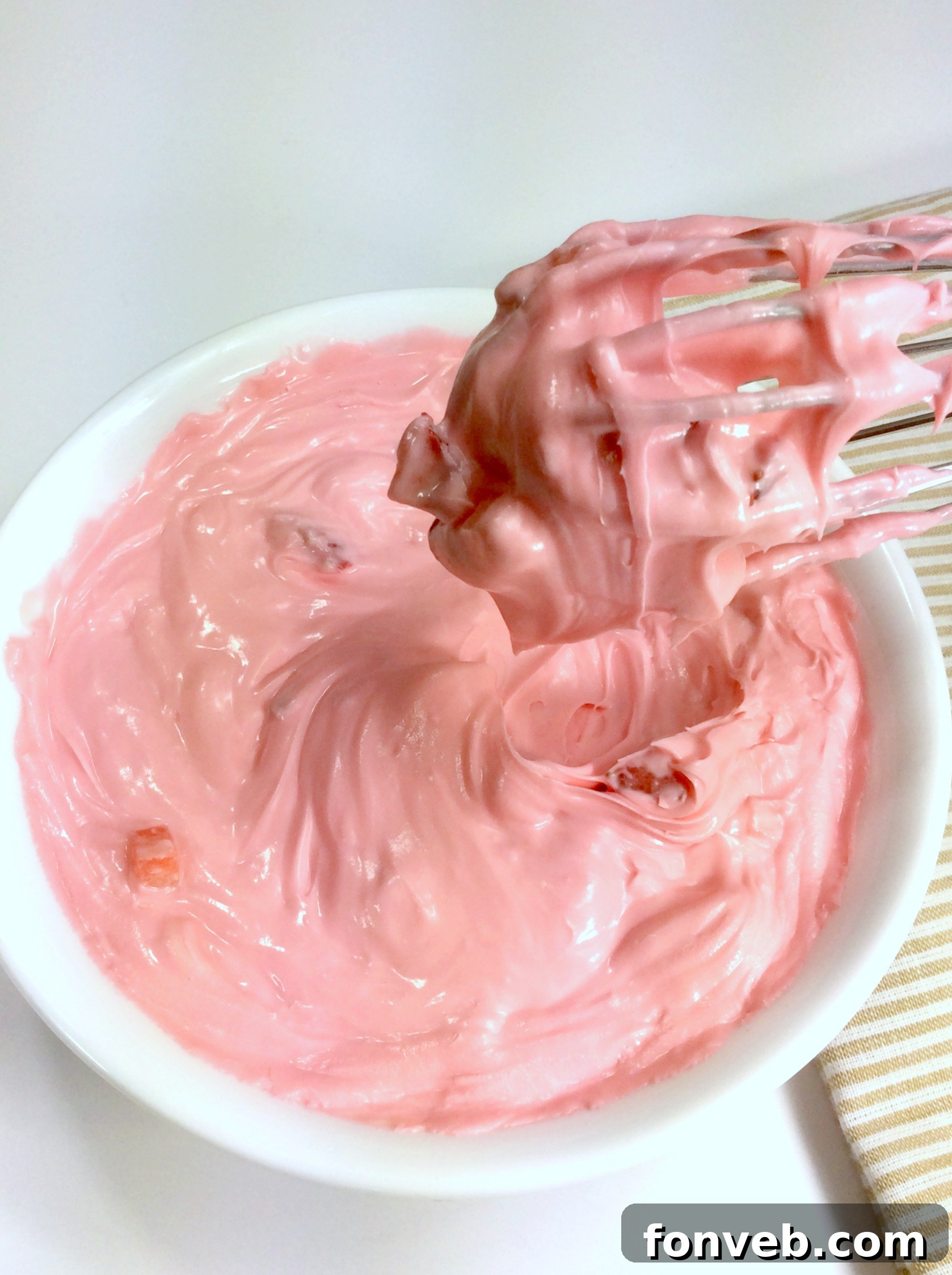 Close-up of a white cake generously frosted with homemade strawberry buttercream.