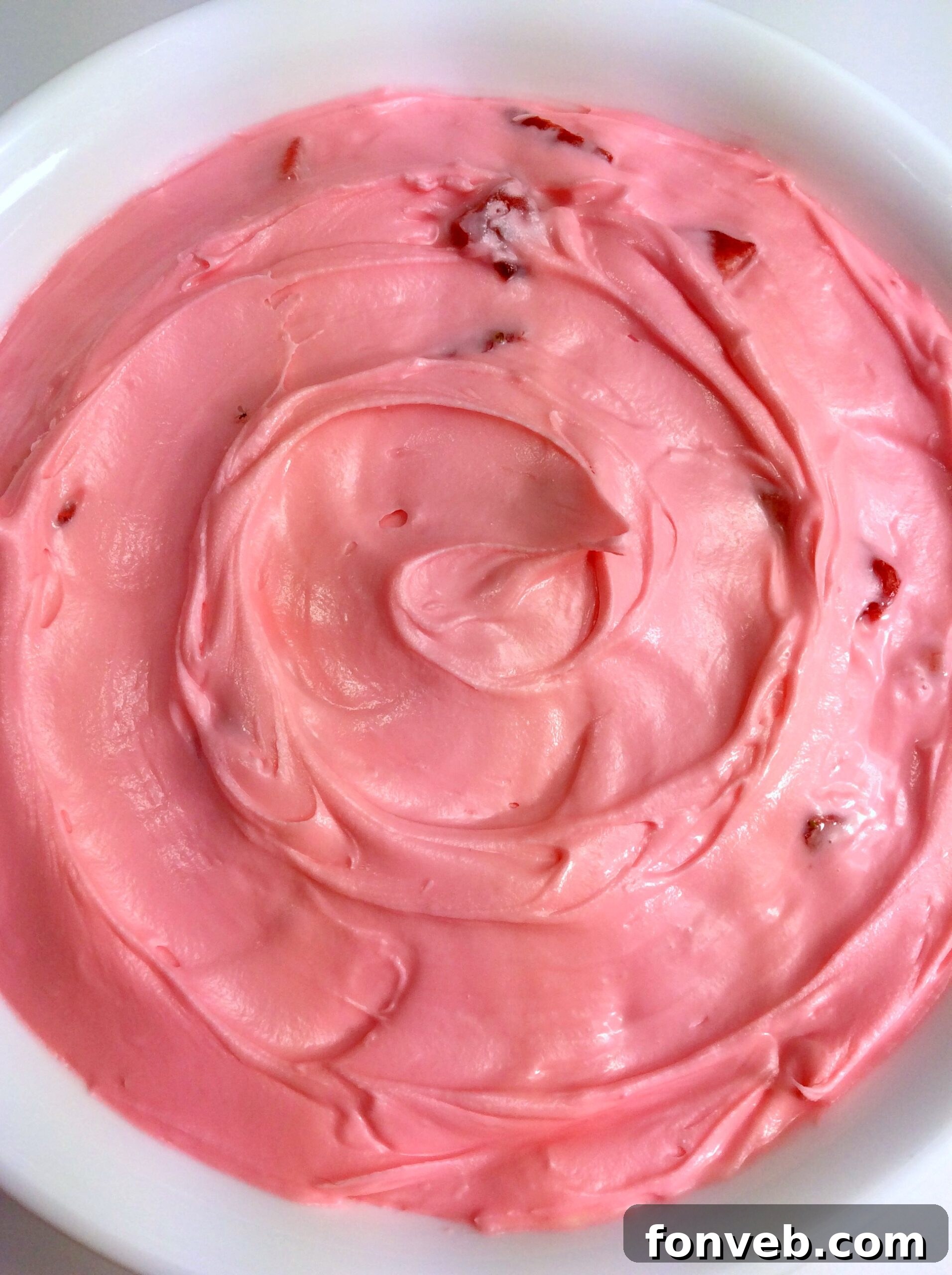 A beautifully decorated cake with strawberry buttercream and fresh strawberry slices.