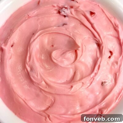 A top-down view of a freshly frosted strawberry cake slice.