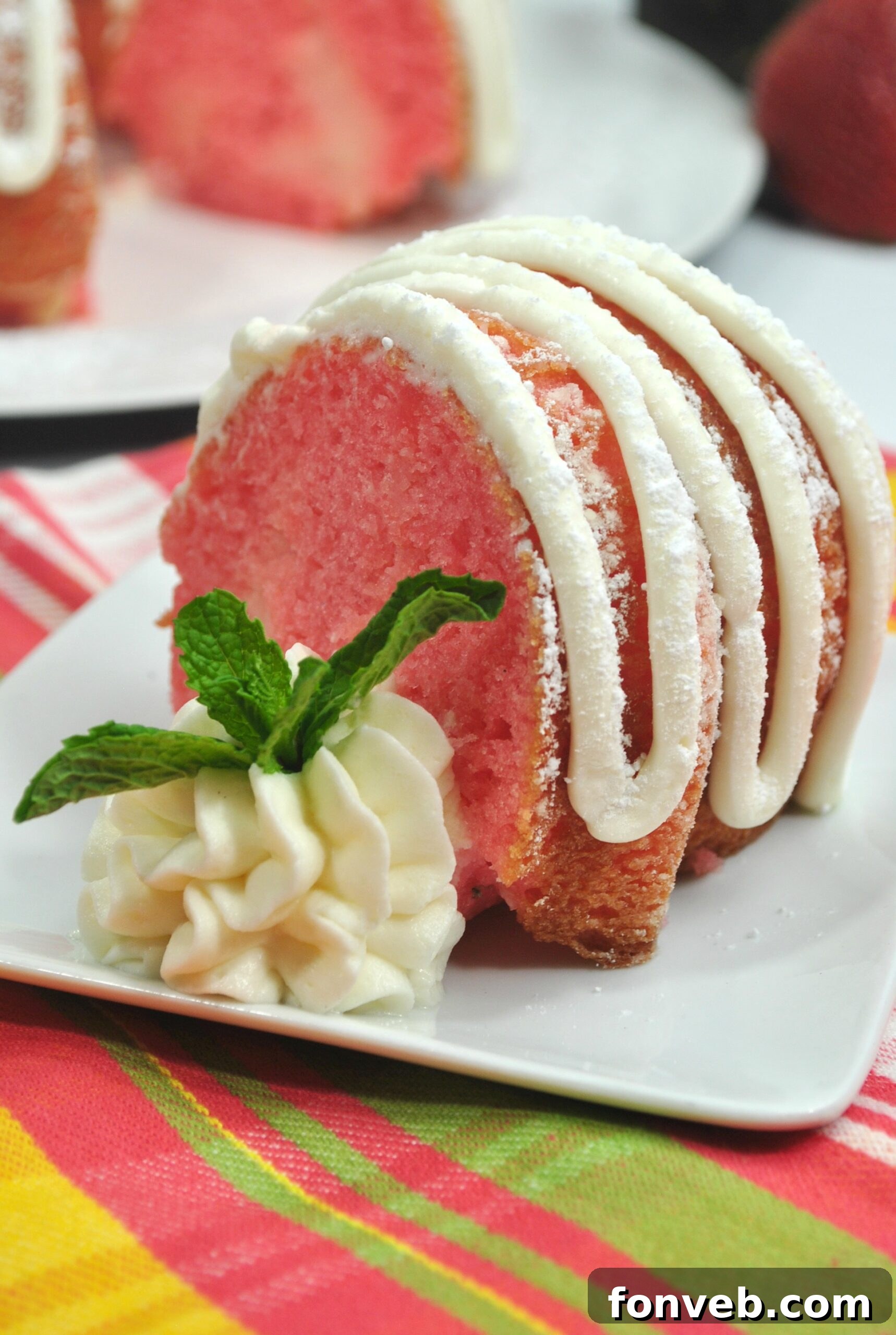 A slice of Strawberries & Cream Bundt Cake on a white plate, highlighting the perfectly baked cake and creamy frosting.