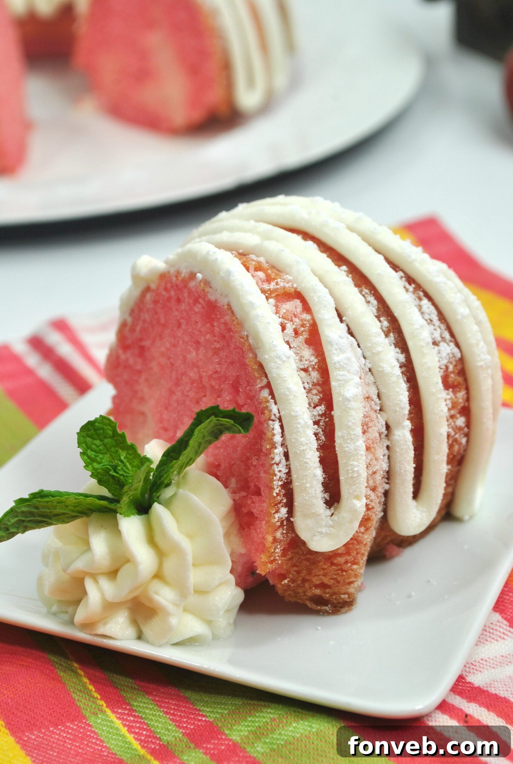 A close-up overhead shot of the Strawberries & Cream Bundt Cake, showing the intricate design of the bundt pan and the drizzle of frosting.