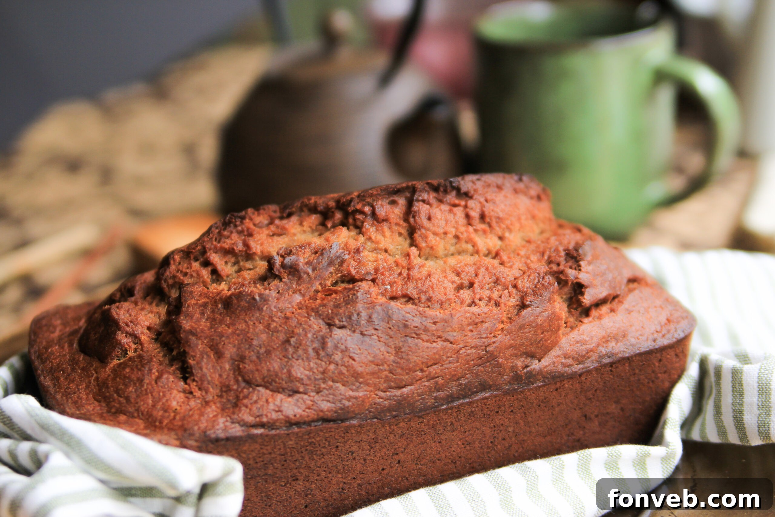Three golden brown loaves of homemade banana bread, stacked on a wooden board