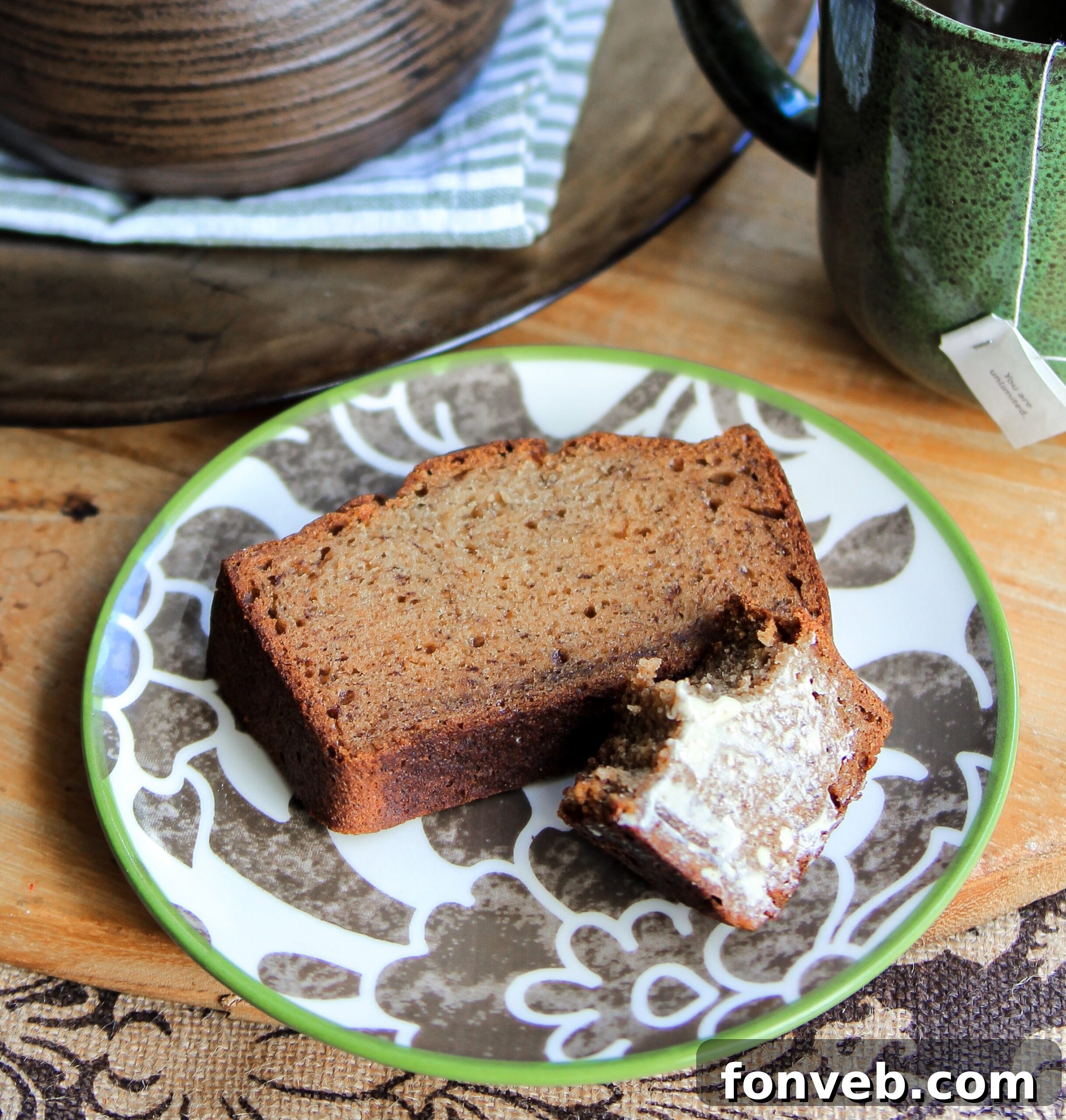 A whole loaf of simple banana bread on a wooden cutting board with a knife and a few slices