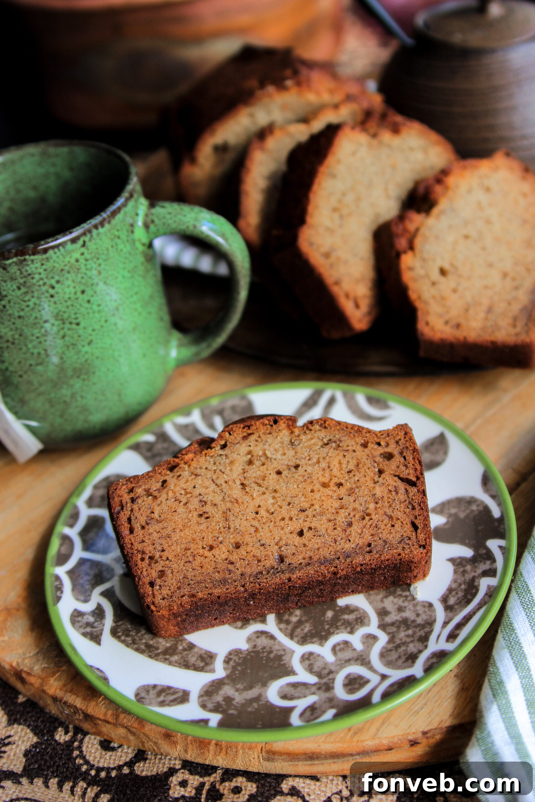 A close-up shot of a thick, inviting slice of simple banana bread on a crisp white plate