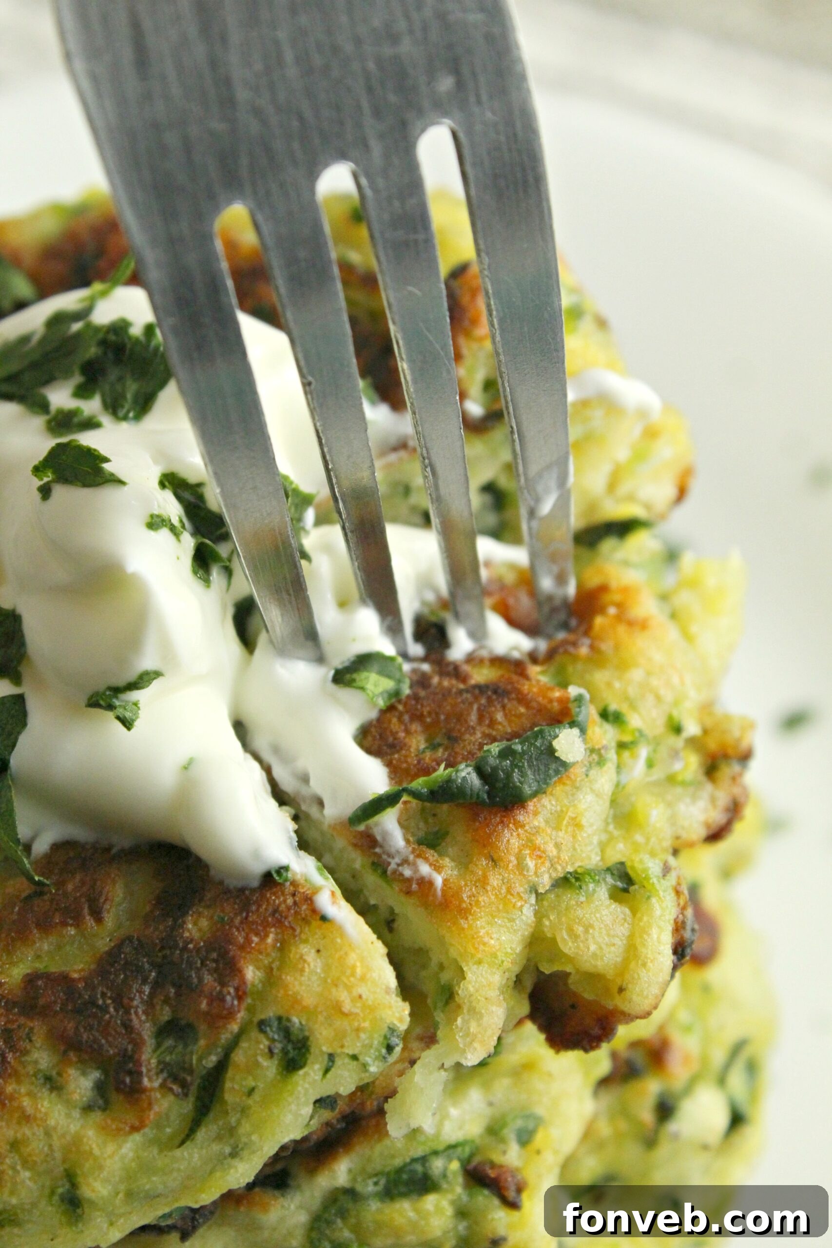 A close-up shot of a cheesy zucchini pancake being flipped in a hot skillet