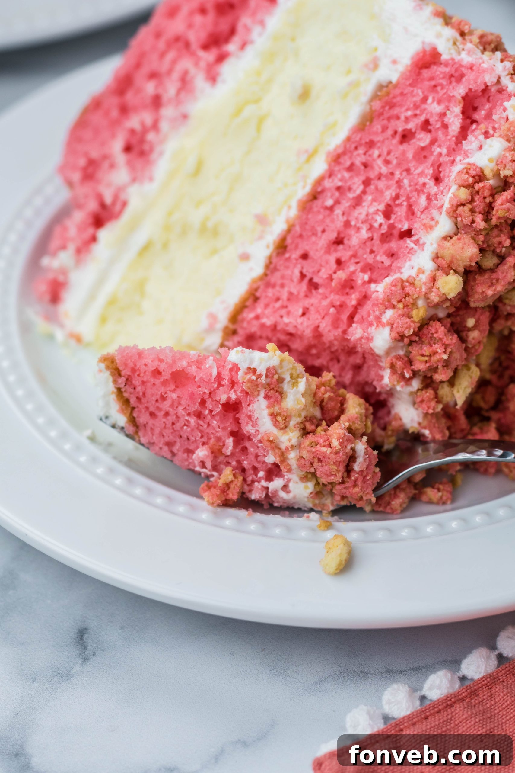Ultimate Strawberry Shortcake Cheesecake 6 A close-up view of a slice of Strawberry Shortcake Cheesecake Cake, with a fork gently taking a bite, highlighting the moist cake, creamy cheesecake, and textured crumble.
