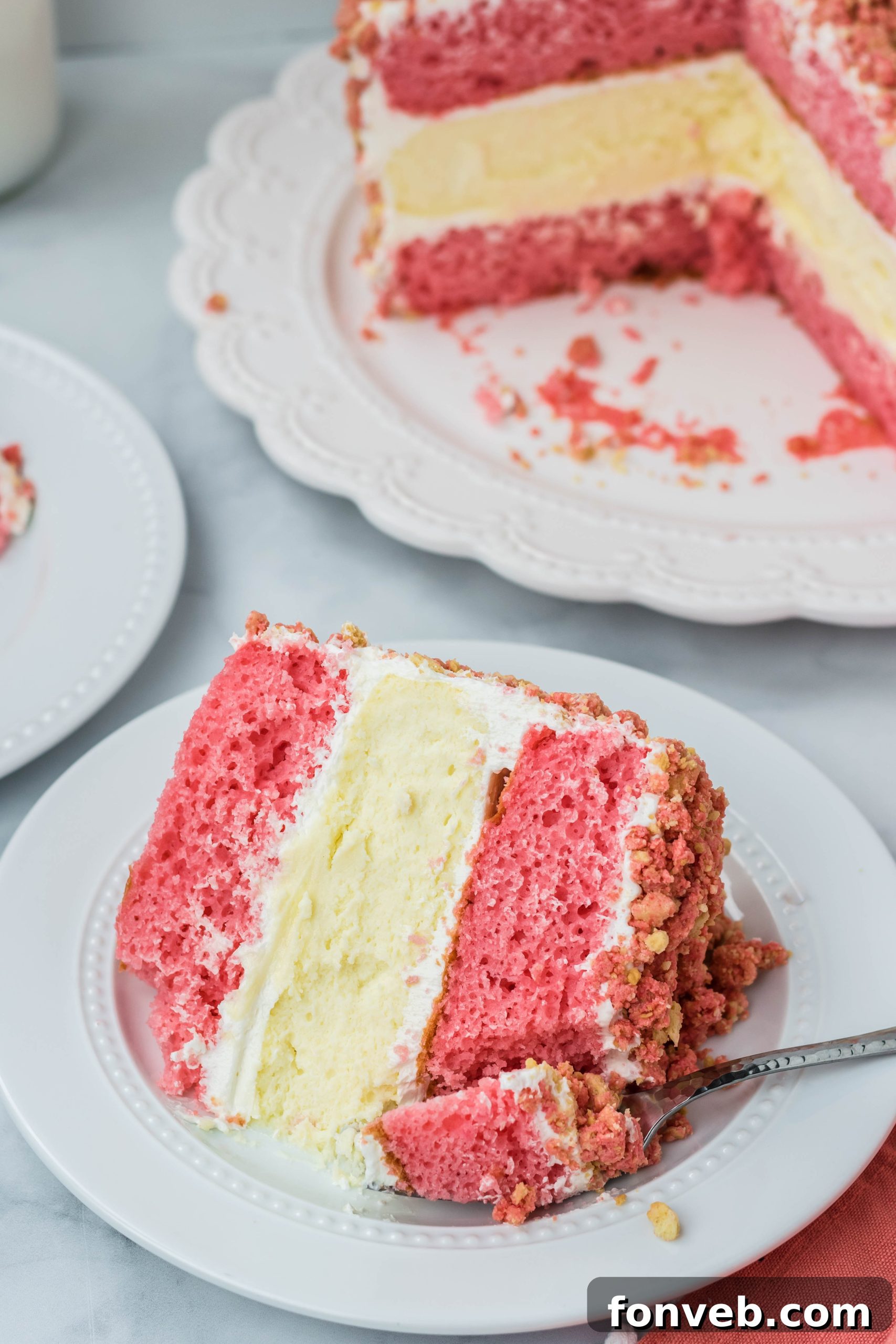 Ultimate Strawberry Shortcake Cheesecake 7 Overhead shot of the Strawberry Shortcake Cheesecake Cake on a white plate, with a fork taking a bite out, showing the rich strawberry and cream layers.