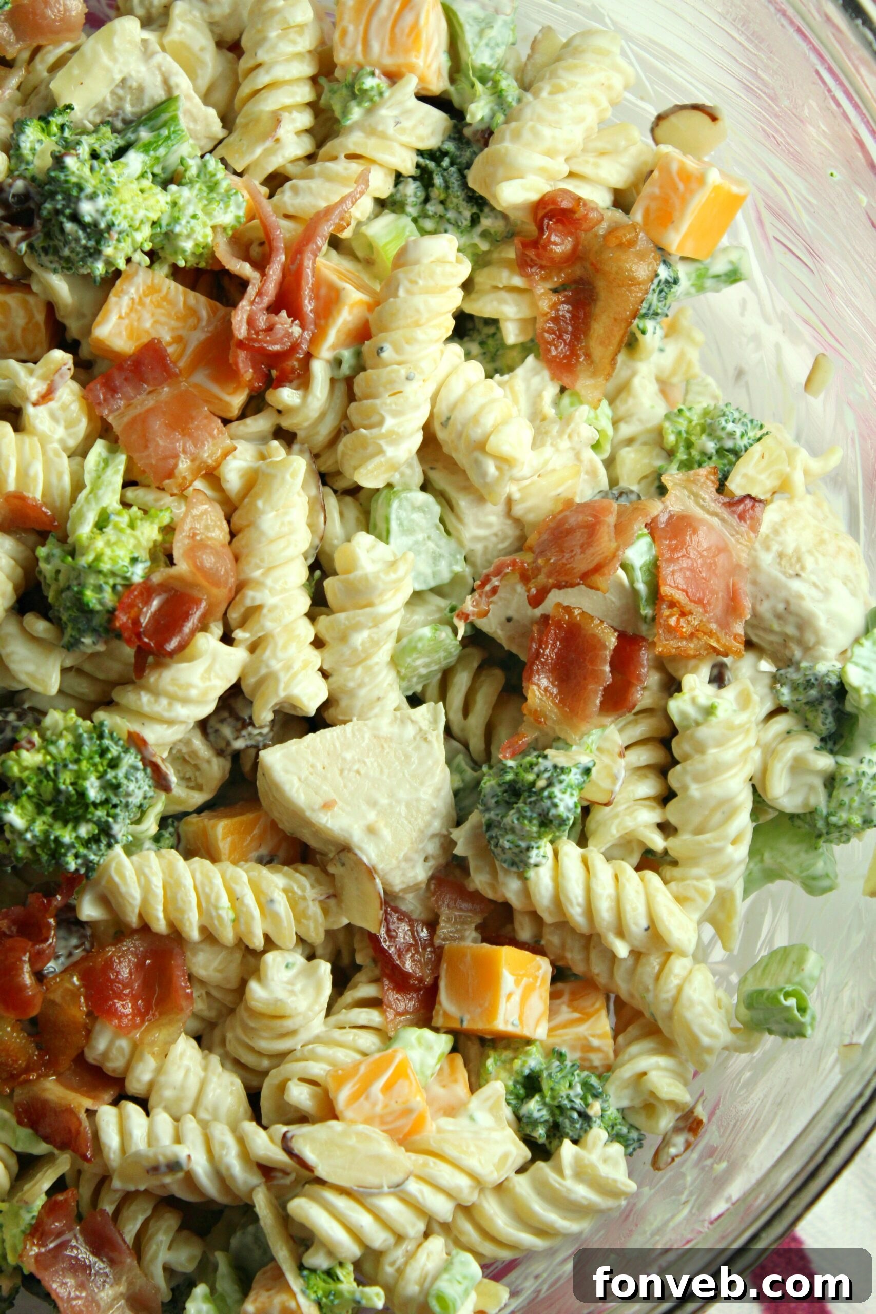 Chicken Bacon Broccoli Pasta Salad closeup in a white bowl with a bamboo spoon