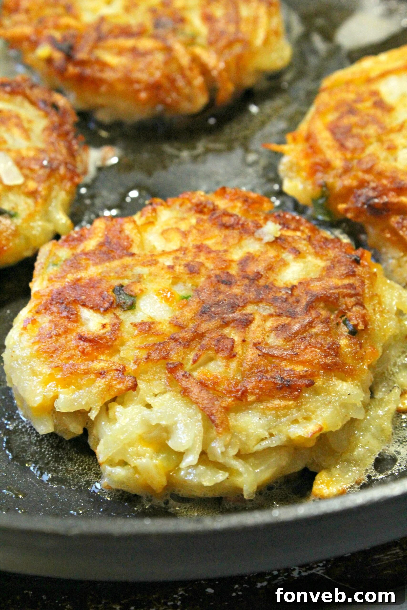 Golden brown crispy cheesy hash brown patties on a skillet, ready to be served.