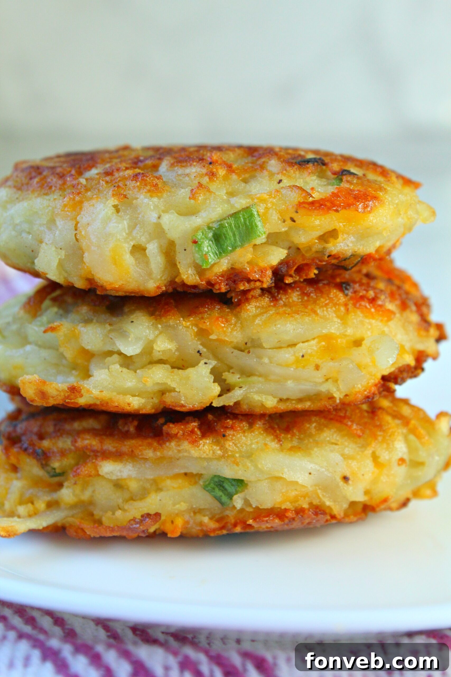 Hash brown patties topped with sour cream and fresh herbs, ready for eating.
