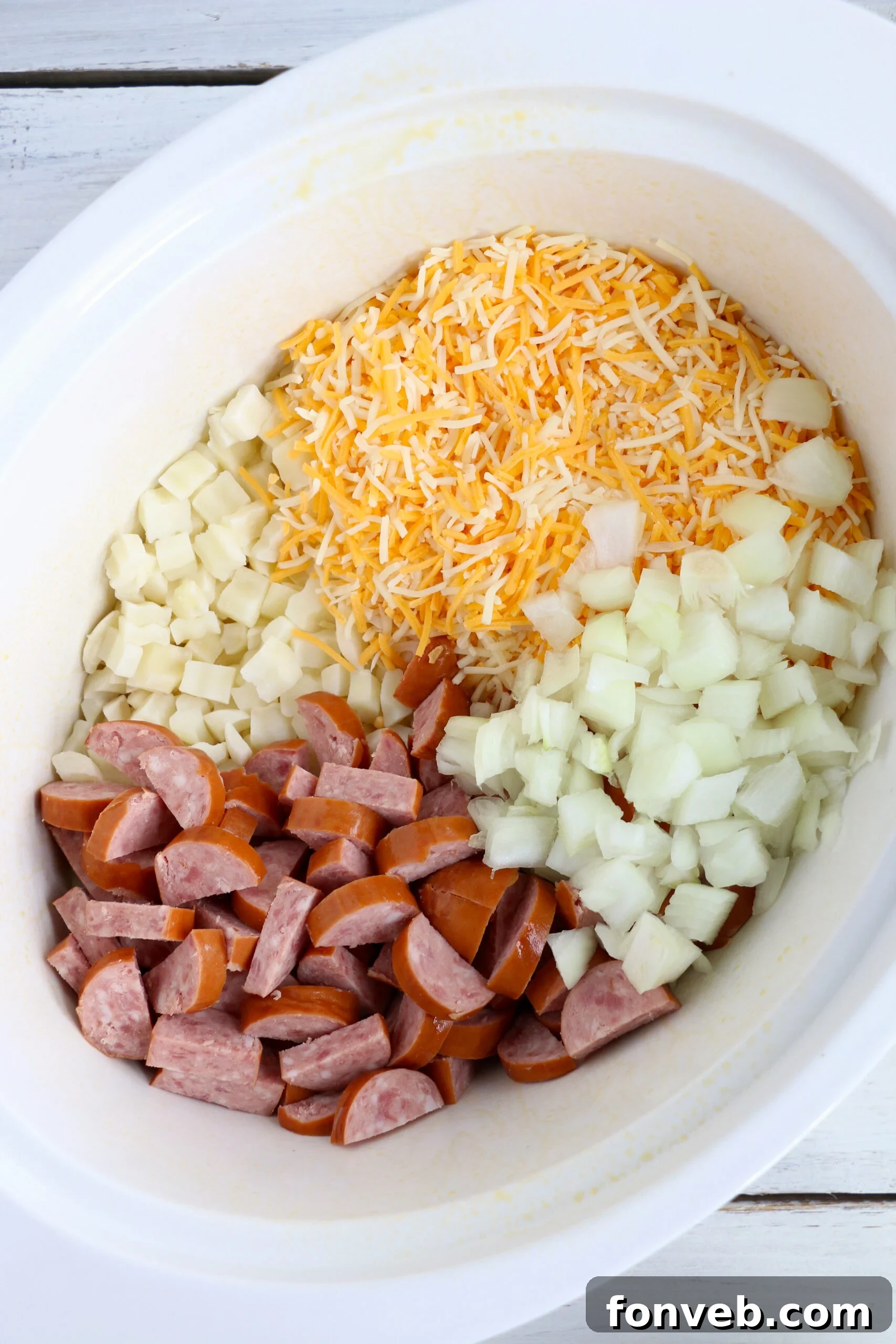 Overhead view of Slow Cooker Cheesy Kielbasa Hashbrown Casserole with a spoon scooping out a portion.