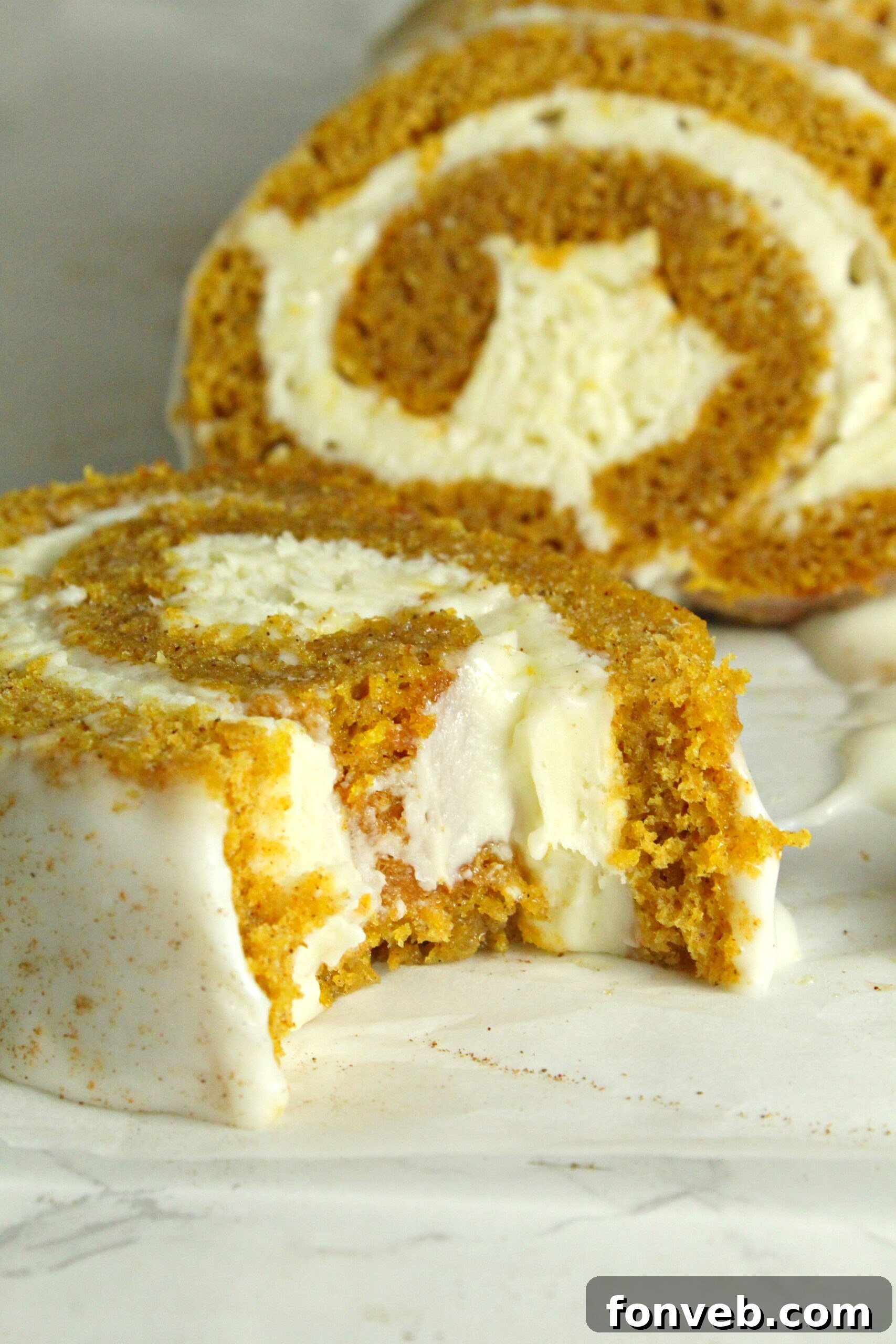 Deliciously moist pumpkin cake roll with cream cheese frosting, sliced to reveal perfect swirls.