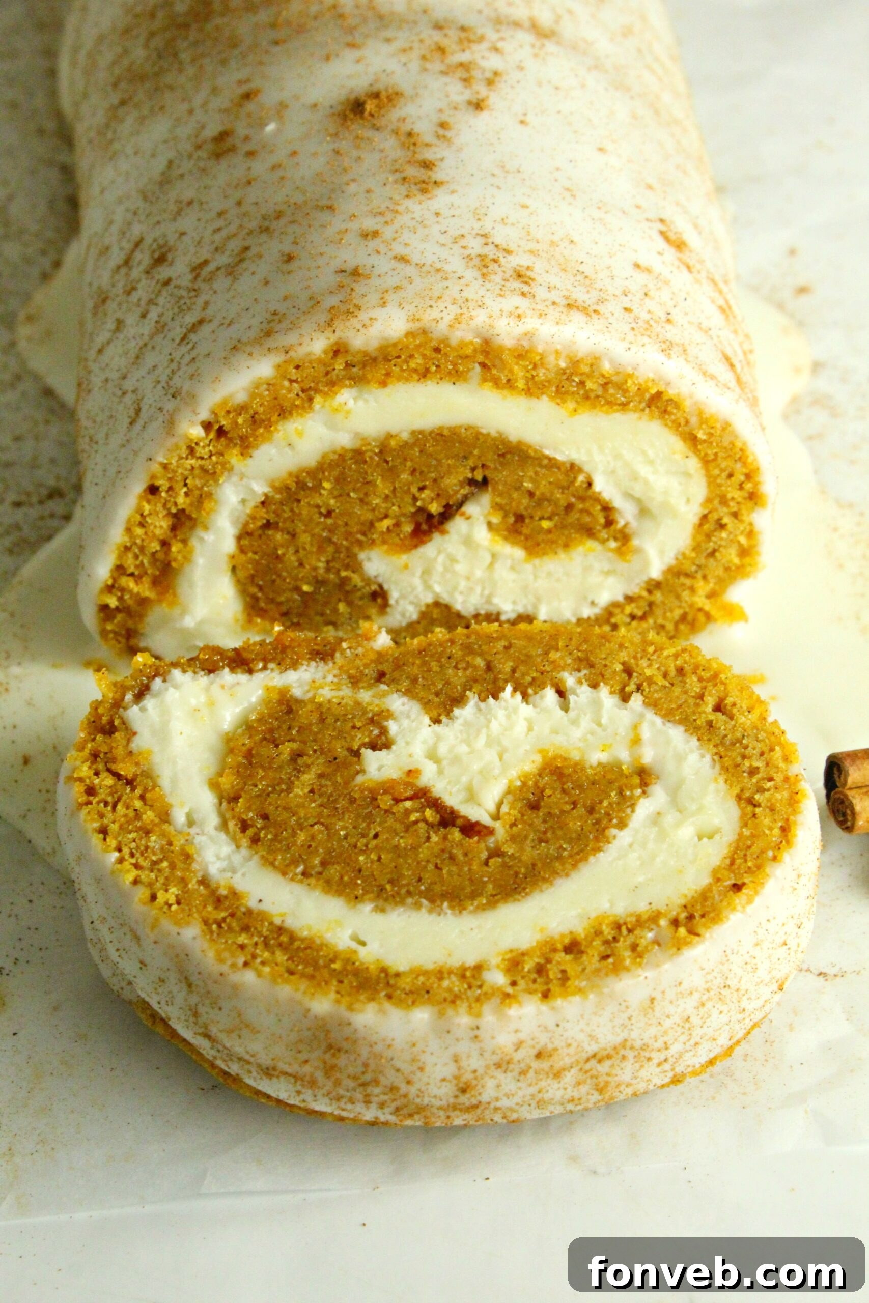 Close-up of the pumpkin cake roll showing the golden cake and white cream cheese filling.