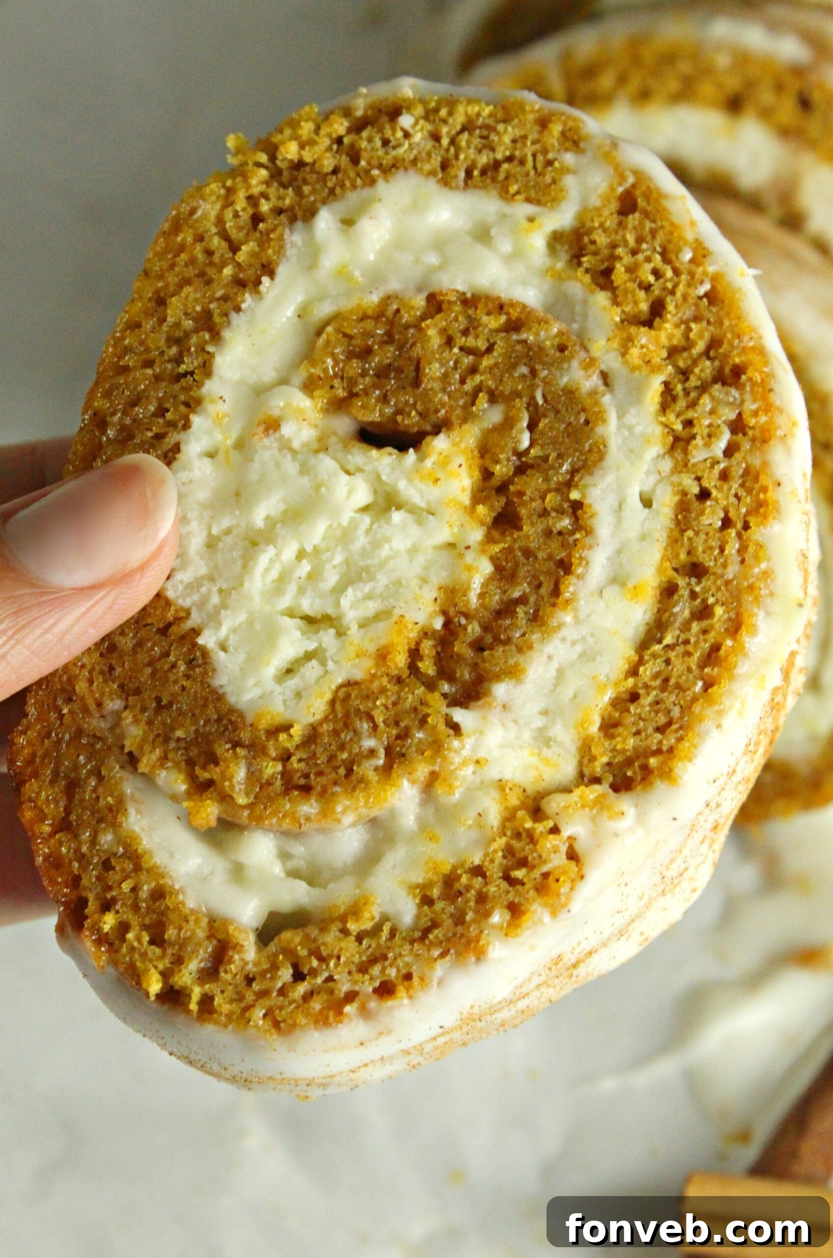 A close-up of a pumpkin cake roll slice, emphasizing the beautiful cake and frosting layers.