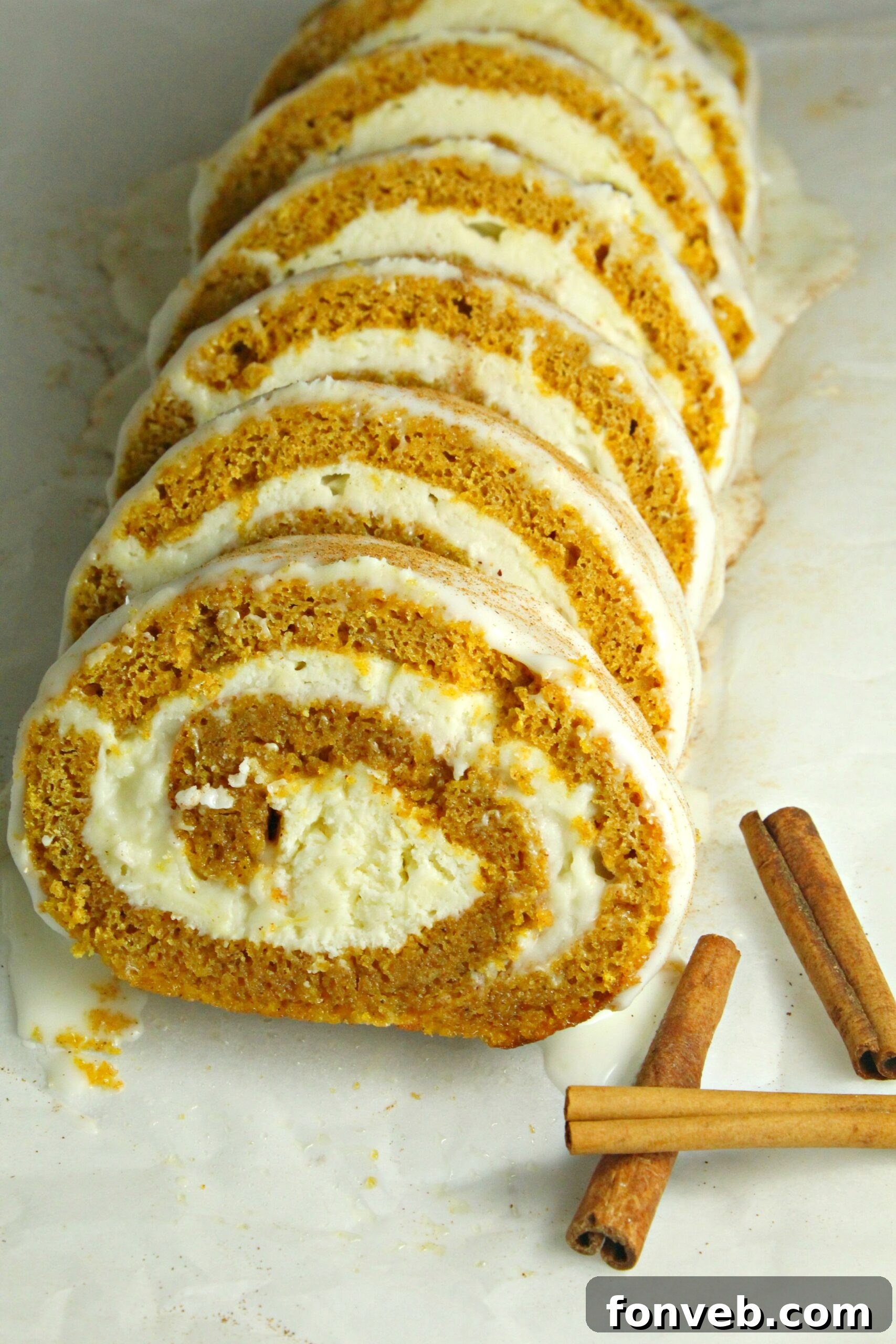 The pumpkin roll on a cutting board with a knife, ready for slicing.
