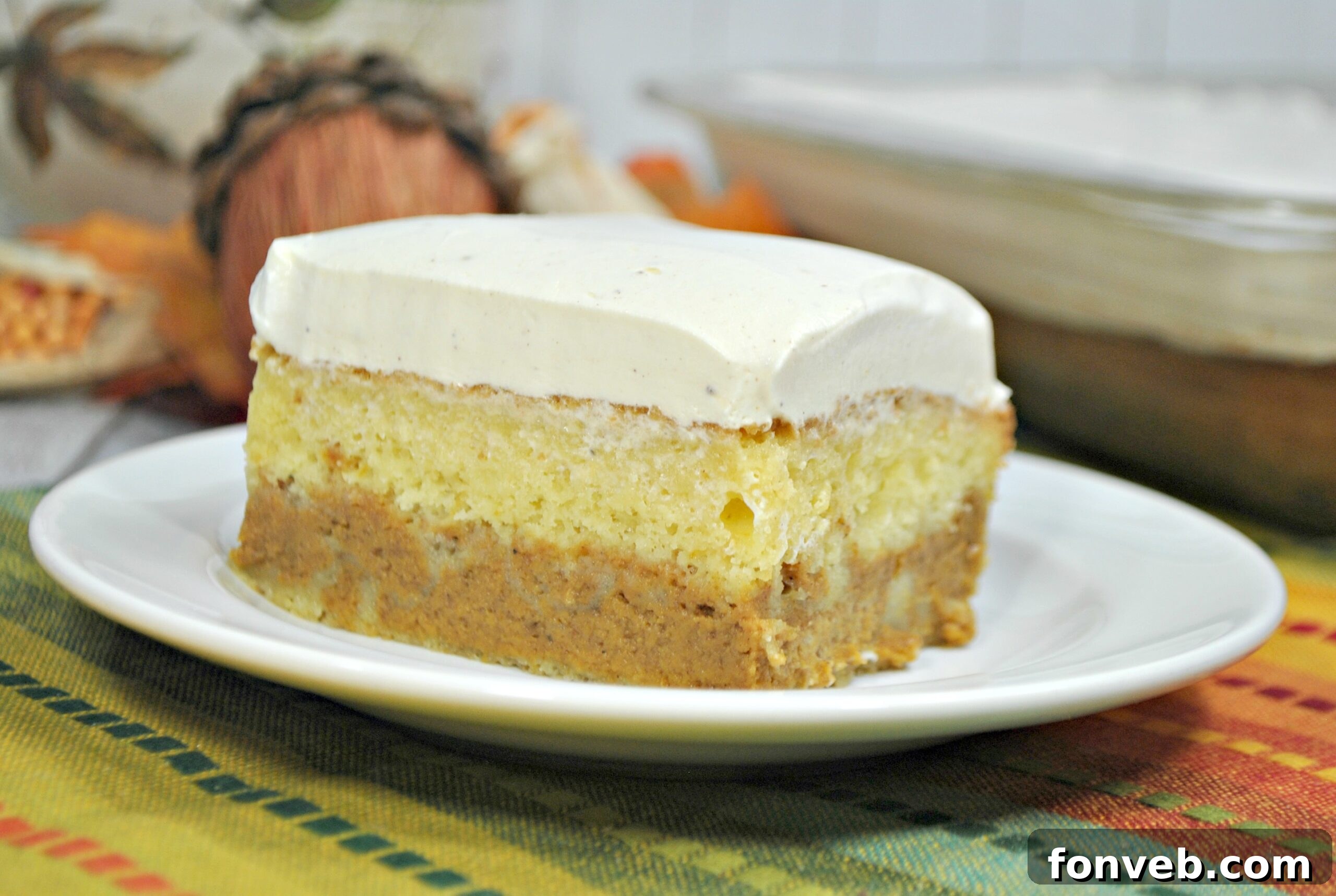 Enchanted Pumpkin Dream Cake 4 A whole Pumpkin Magic Cake adorned with generous swirls of vanilla cream cheese frosting, ready for slicing.