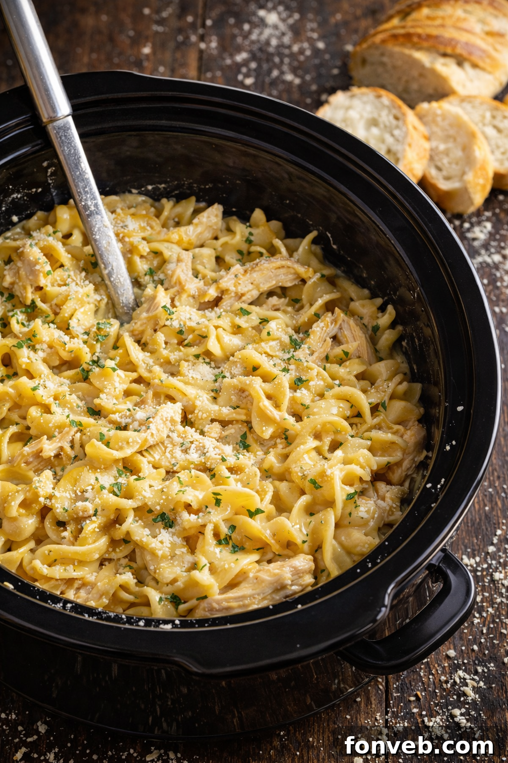 Close-up shot of creamy Slow Cooker Chicken and Noodles in a stoneware slow cooker, showcasing the tender chicken and thick noodles.