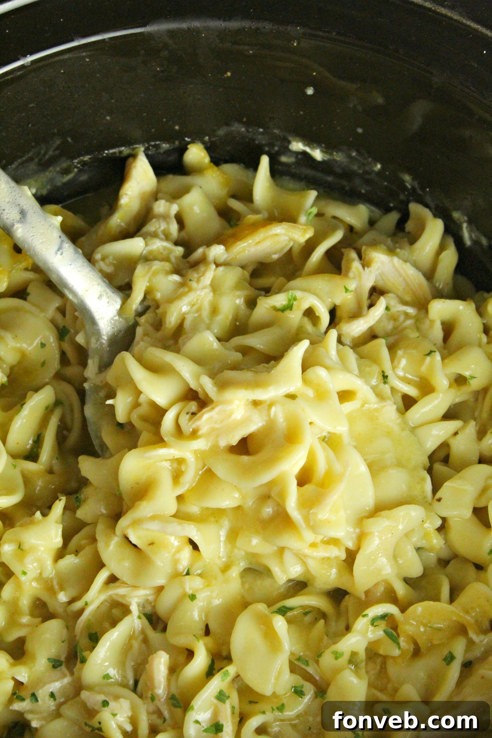 Slow Cooker Chicken and Noodles simmering gently in the slow cooker, a comforting and inviting scene.