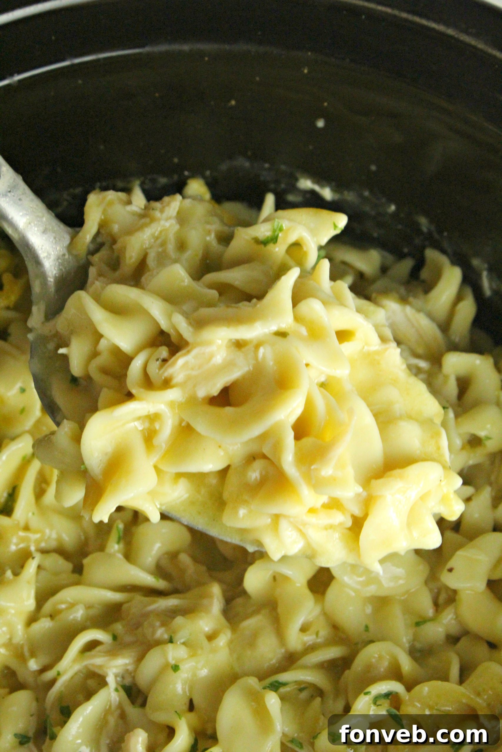Slow Cooker Chicken and Noodles cooking in a slow cooker, steam rising from the delicious, creamy contents.