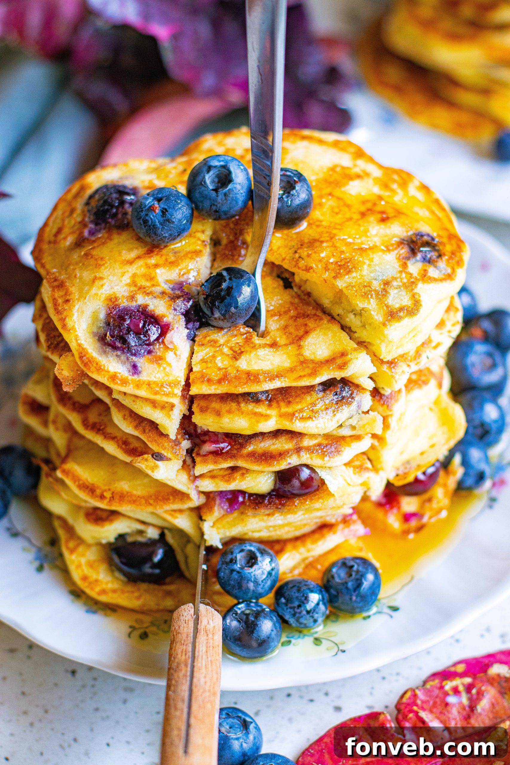 A stack of golden, fluffy blueberry cream cheese pancakes, topped with a melting pat of butter, awaiting syrup.