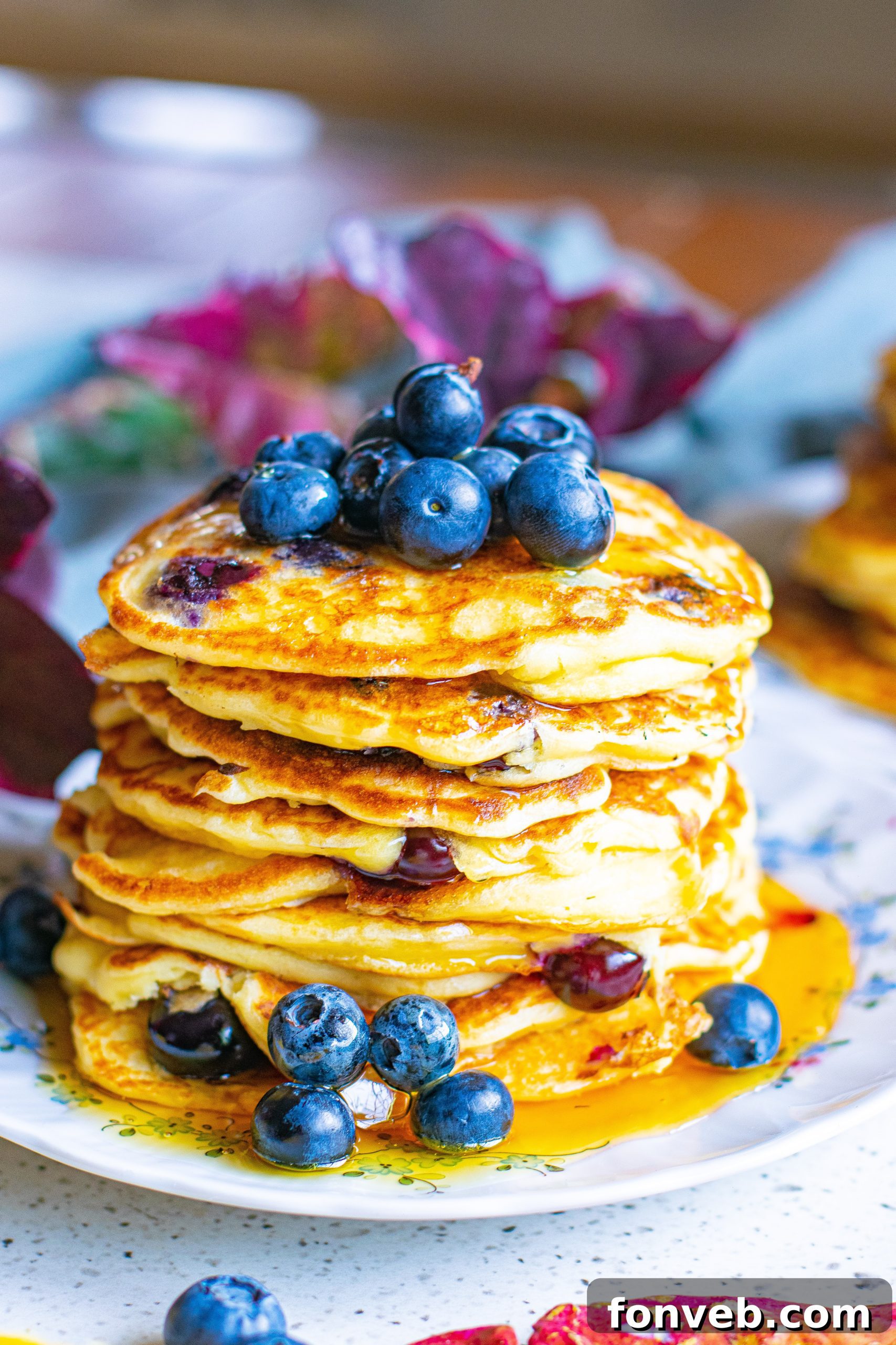 A stunning stack of blueberry cream cheese pancakes, beautifully plated with extra blueberries and rich maple syrup, ready to be enjoyed.
