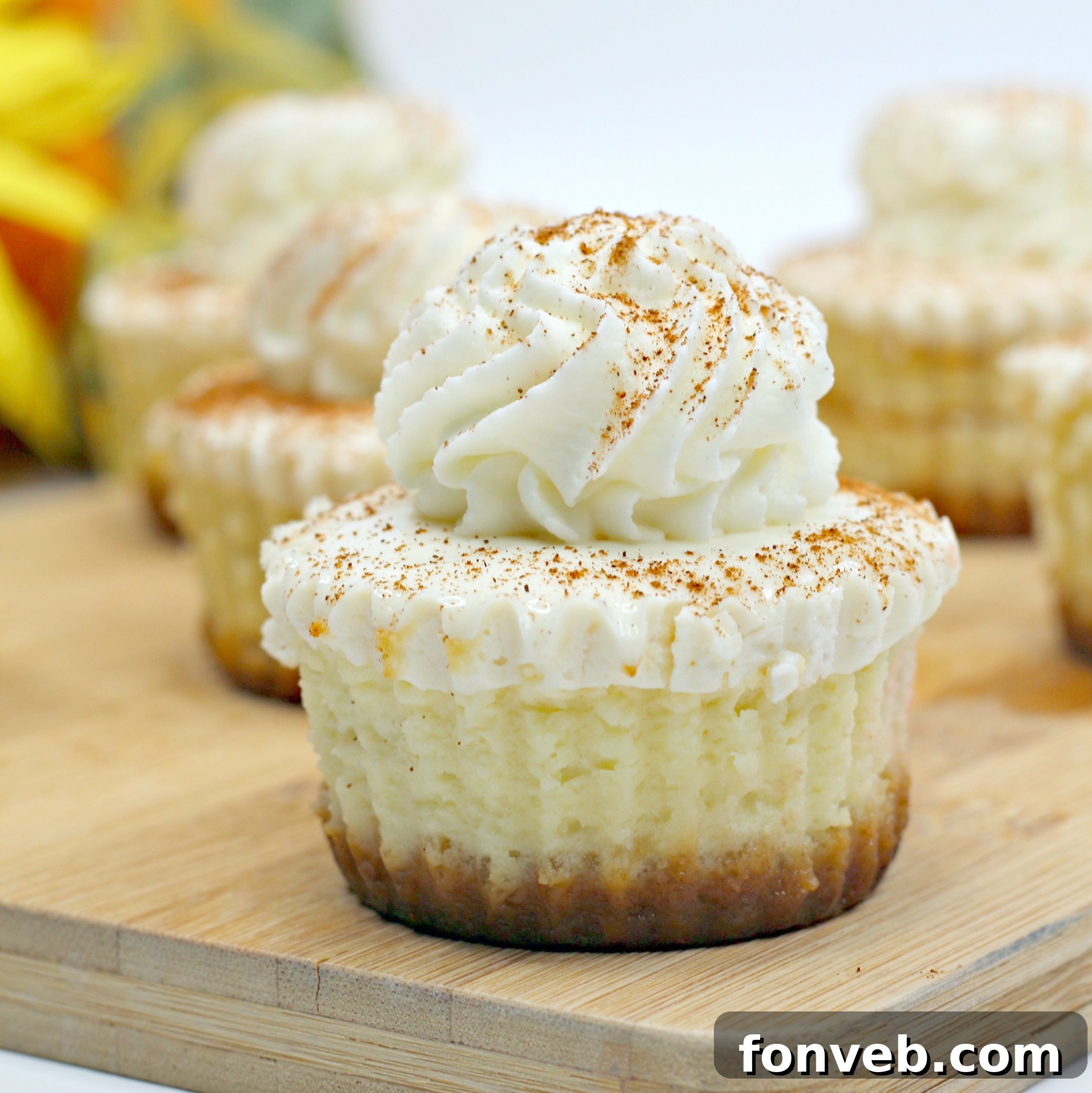 A stack of three Pumpkin Swirl Cheesecakes, beautifully topped with whipped cream and a sprinkle of cinnamon, ready to be enjoyed