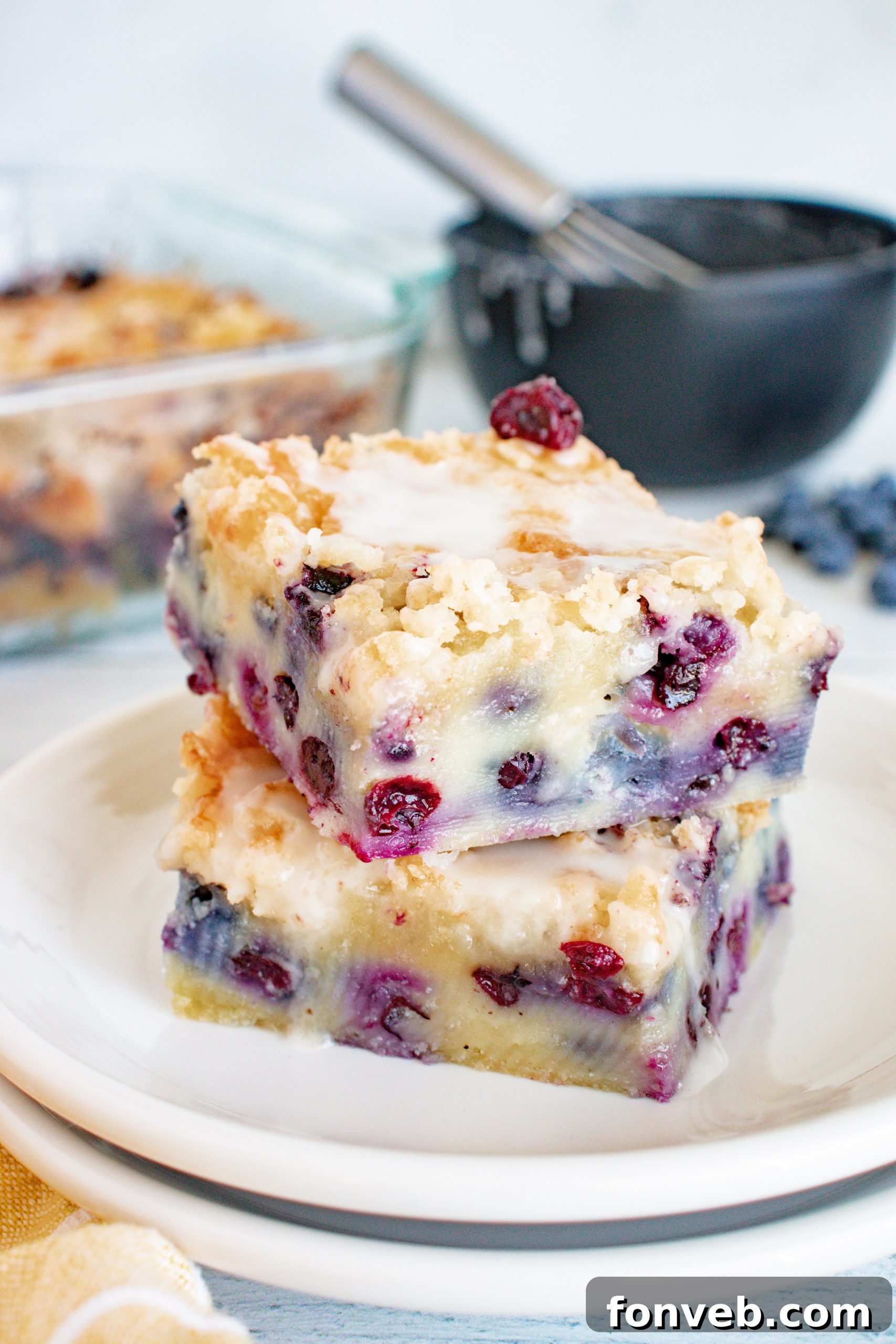 Blueberry Muffin Crumble Cake with Vanilla Drizzle 2 Close-up of a slice of moist blueberry muffin cake with streusel topping and vanilla glaze, showing juicy blueberries.