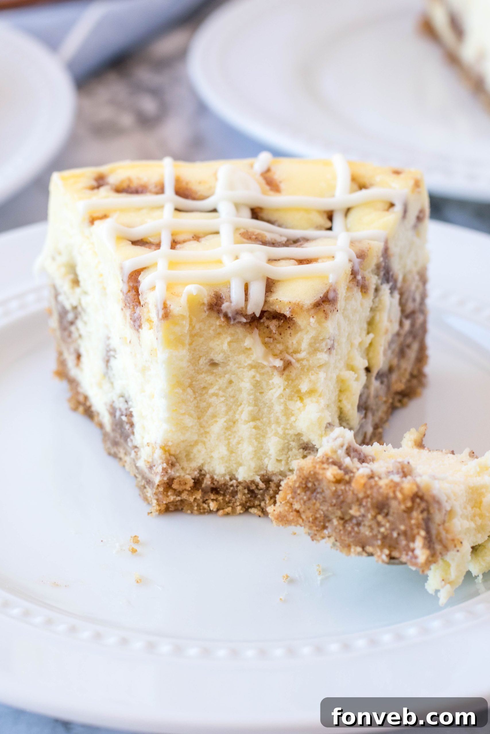 A perfectly sliced Cinnamon Roll Cheesecake revealing its creamy texture and cinnamon swirls, topped with rich cream cheese icing.