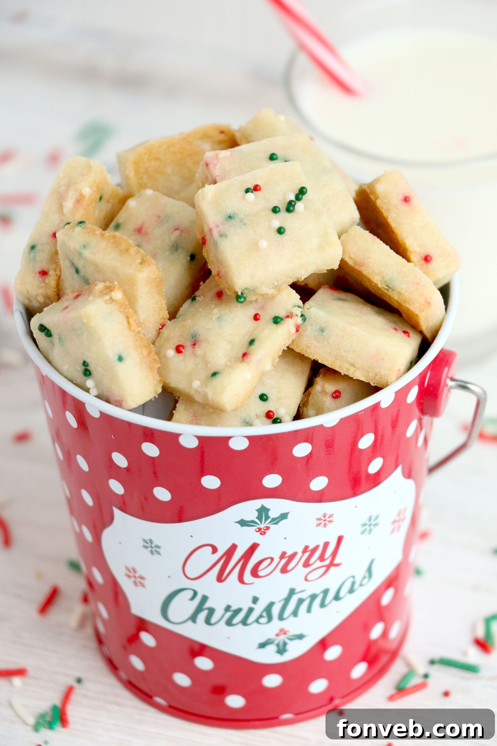 Four Ingredient Festive Shortbread Bites 2 Delicious Christmas Shortbread Cookie Bites, perfectly golden and covered in festive sprinkles, arranged on a rustic platter.